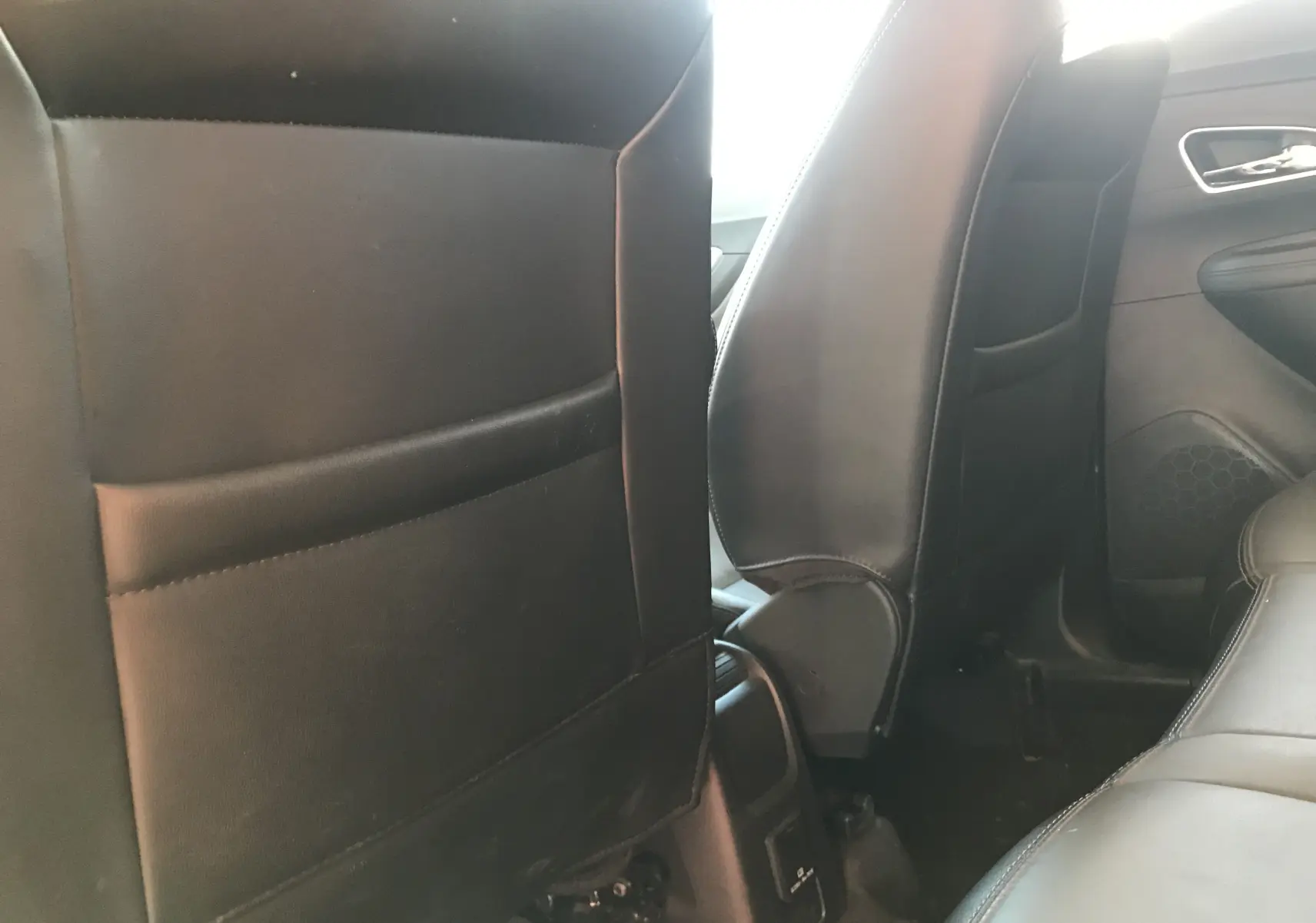 Vue intérieure arrière montrant les dossiers noirs en cuir des sièges avant d'un Opel Mokka blanc de 2015.