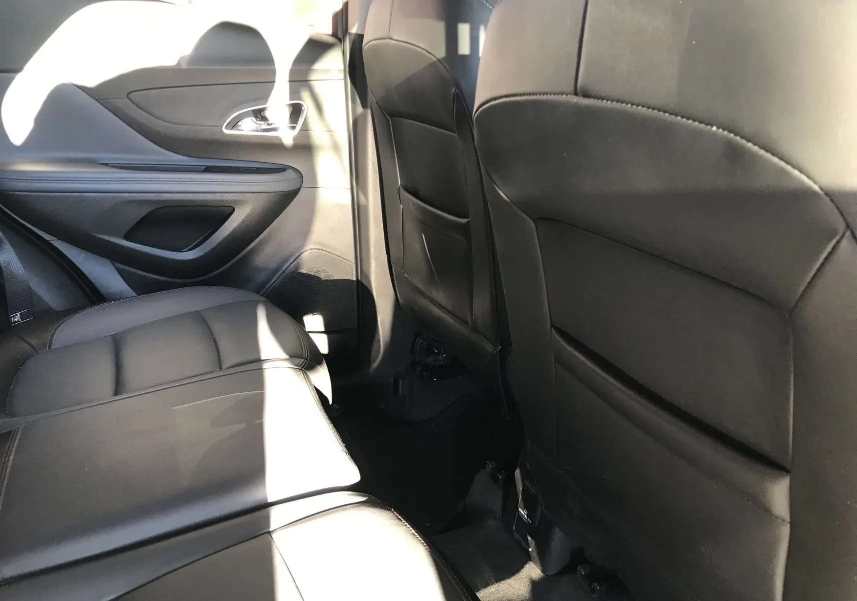 Vue latérale intérieure arrière droite de l'Opel Mokka blanc 2015 avec sièges en cuir noir et finitions soignées.