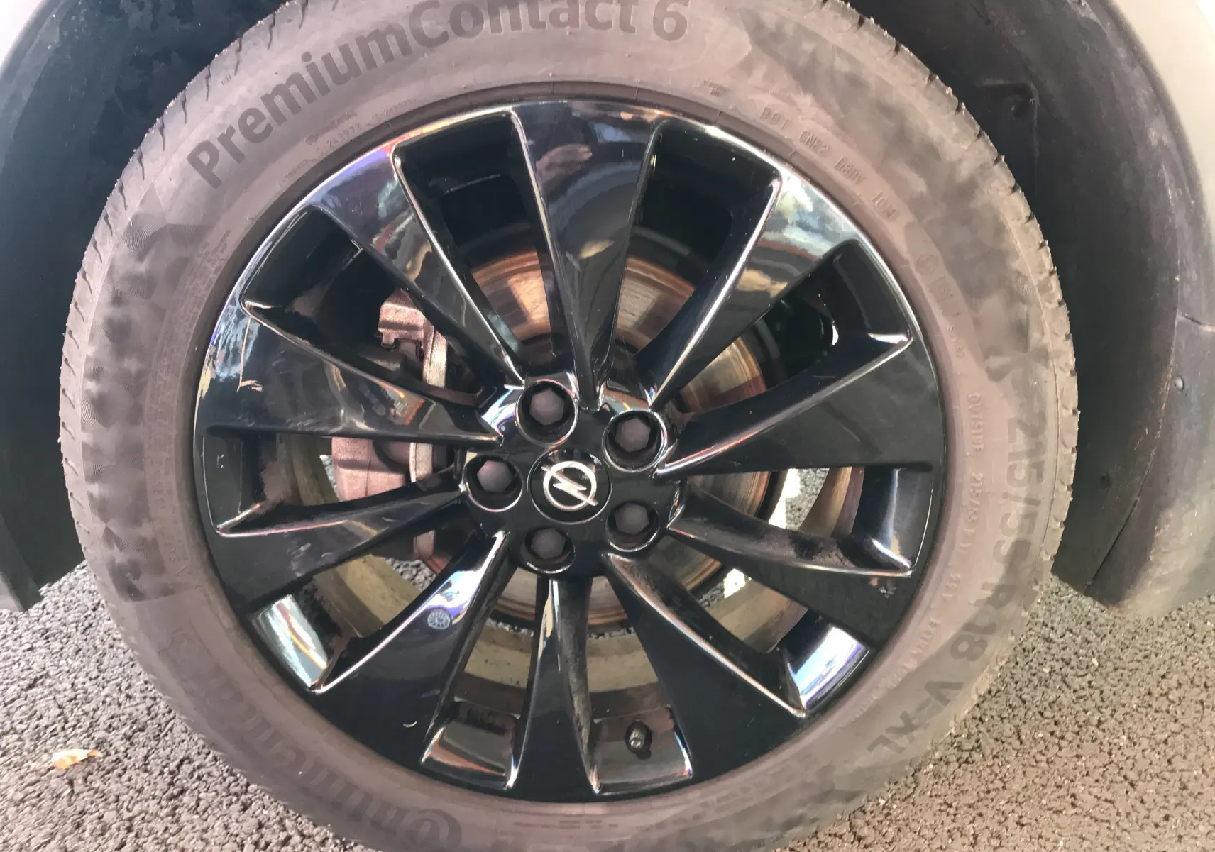 Gros plan sur la roue avant droite d'un Opel Mokka blanc, jante alliage noire brillante avec logo Opel central.