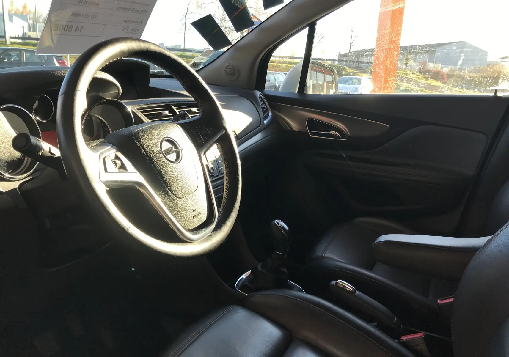Intérieur de l'Opel Mokka blanc vu côté conducteur, volant cuir, tableau de bord et sièges noirs en cuir.