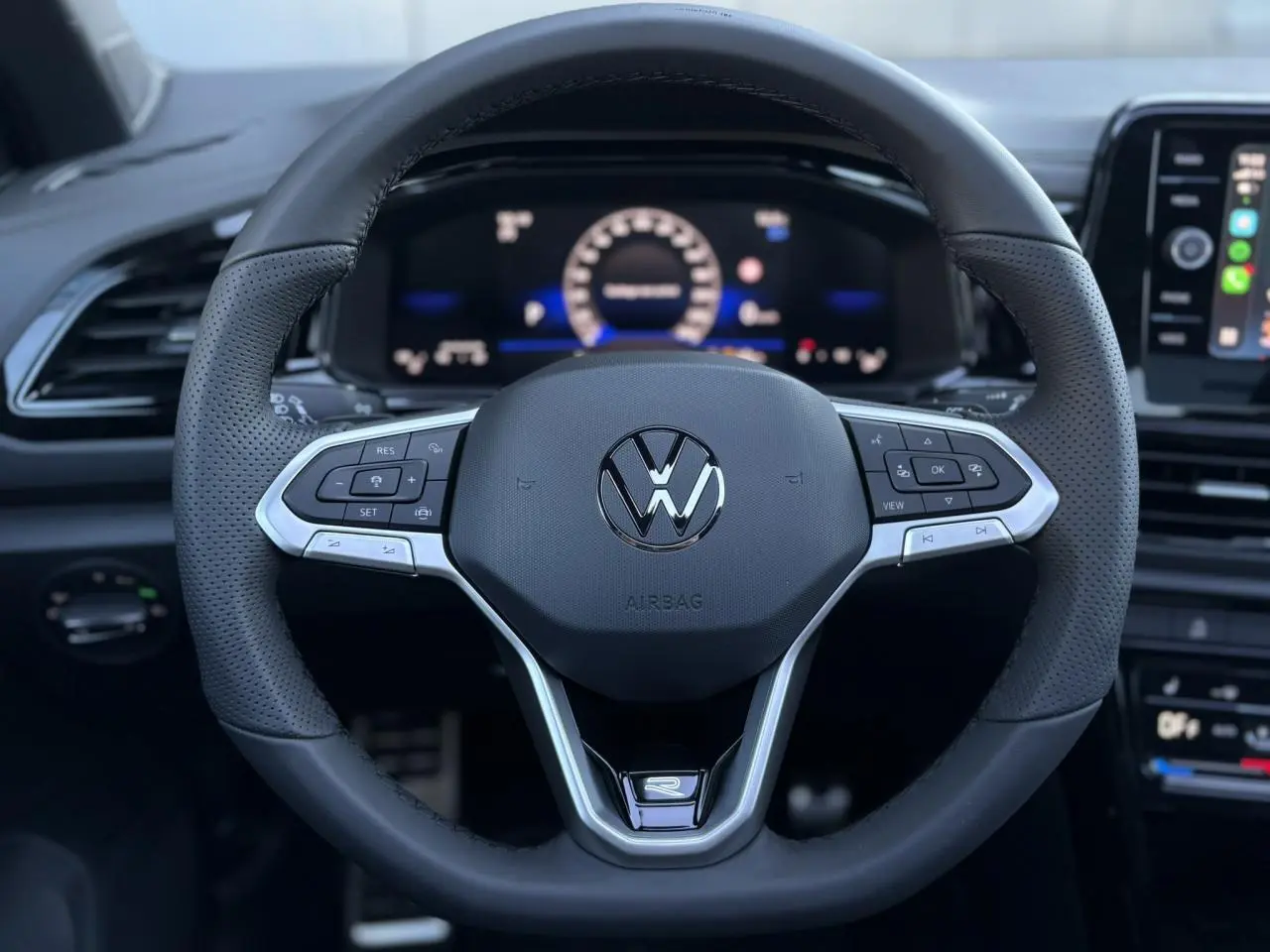 Volant sport noir avec logo VW R-Line au centre, vue frontale du poste de conduite du Volkswagen T-Roc 2025.