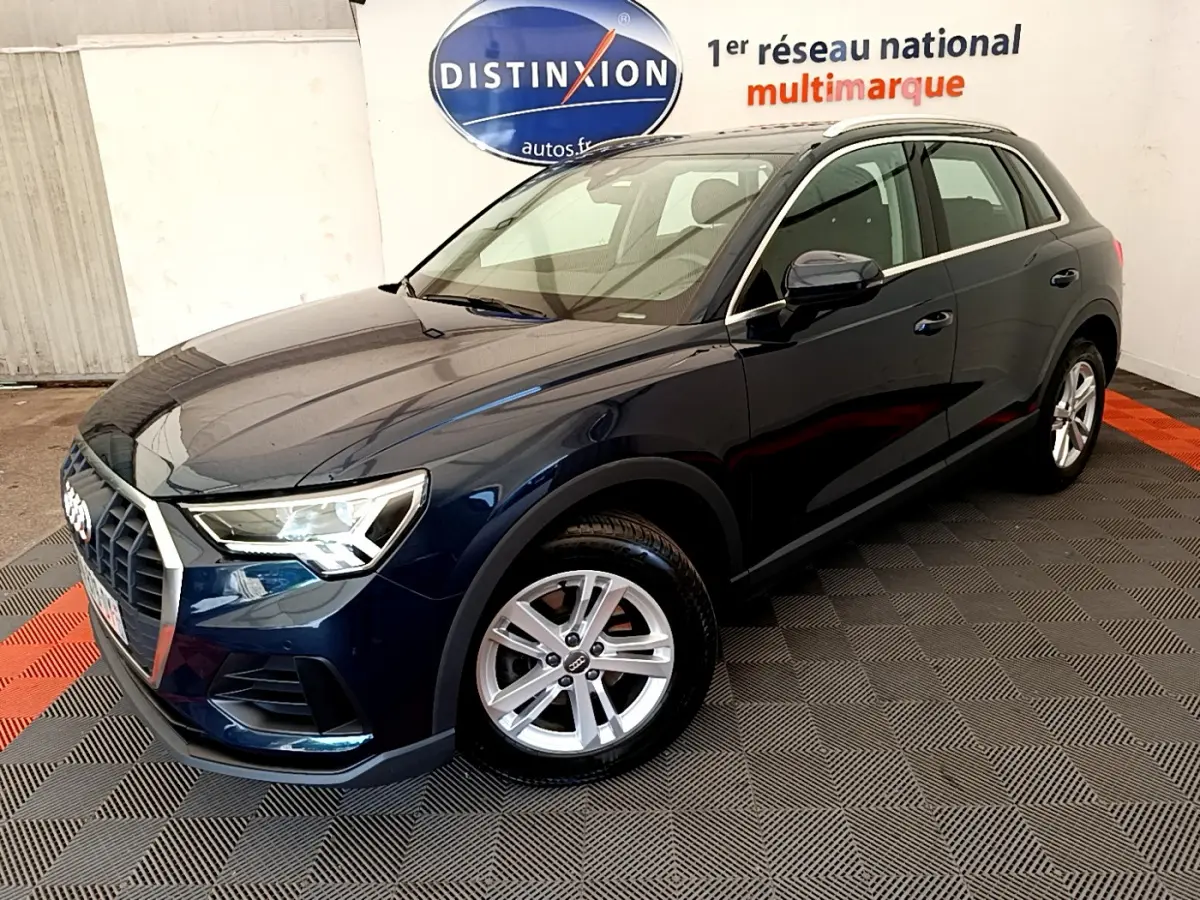 Audi Q3 bleu foncé vu en 3/4 avant droit dans un showroom avec jantes alliage et feux LED allumés.