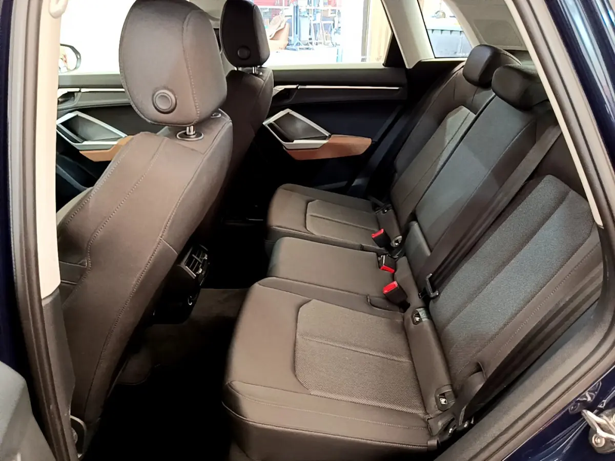 Vue intérieure côté droit des sièges arrière noirs d'un Audi Q3 35 TDI bleu, avec appuie-têtes et ceintures visibles.