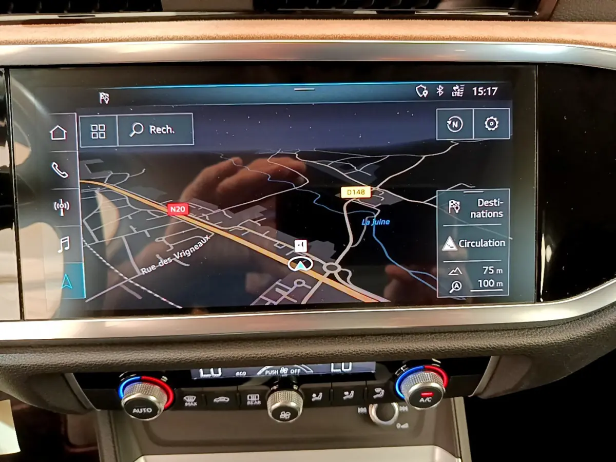 Vue rapprochée de l'écran de navigation et de la console centrale du tableau de bord de l'Audi Q3 bleu 2020.
