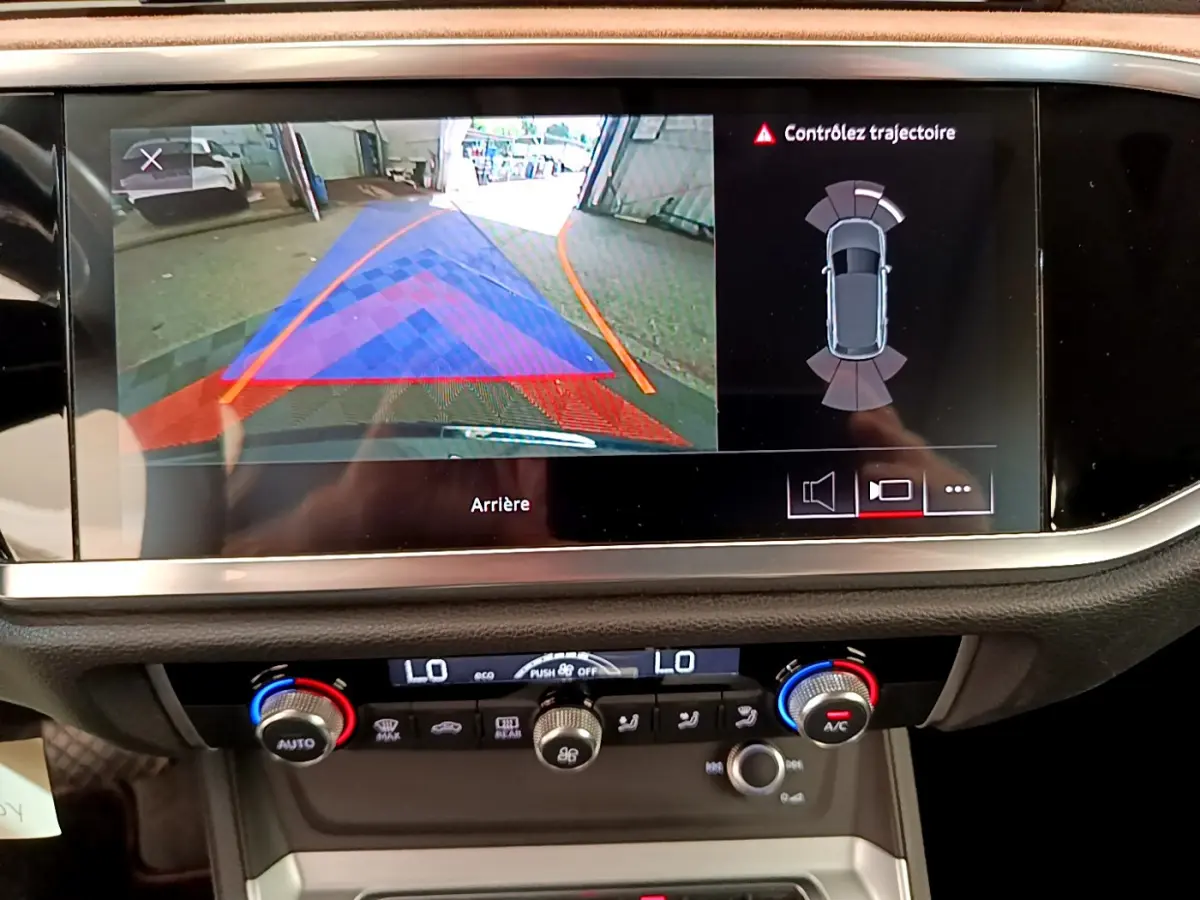 Écran multimédia affichant la caméra de recul et l'aide au stationnement d'un Audi Q3 bleu 2020, vue intérieure centrale.