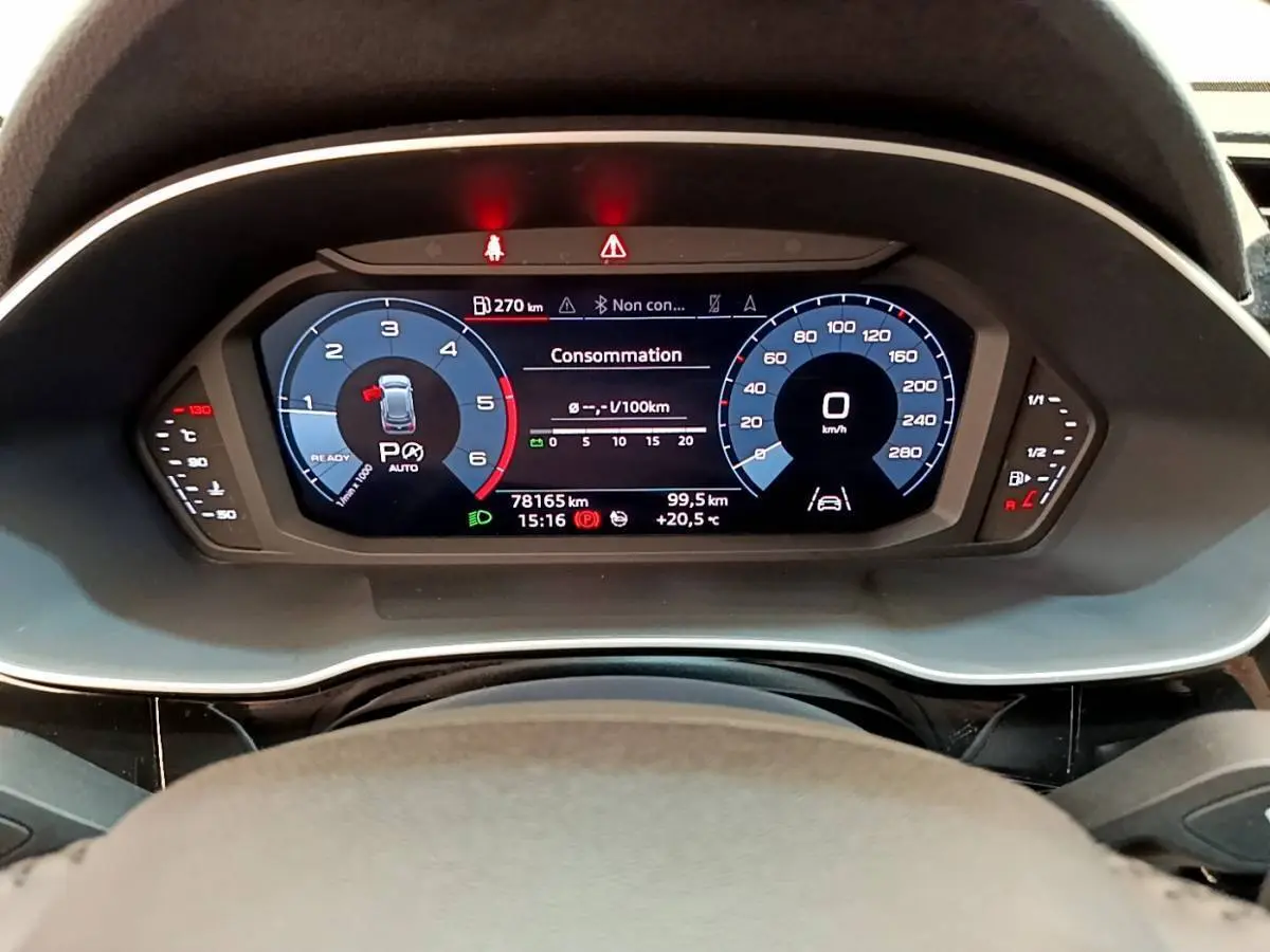 Vue rapprochée du tableau de bord numérique de l'Audi Q3 35 TDI 150 S Tronic Business Line avec affichage consommation et vitesse.