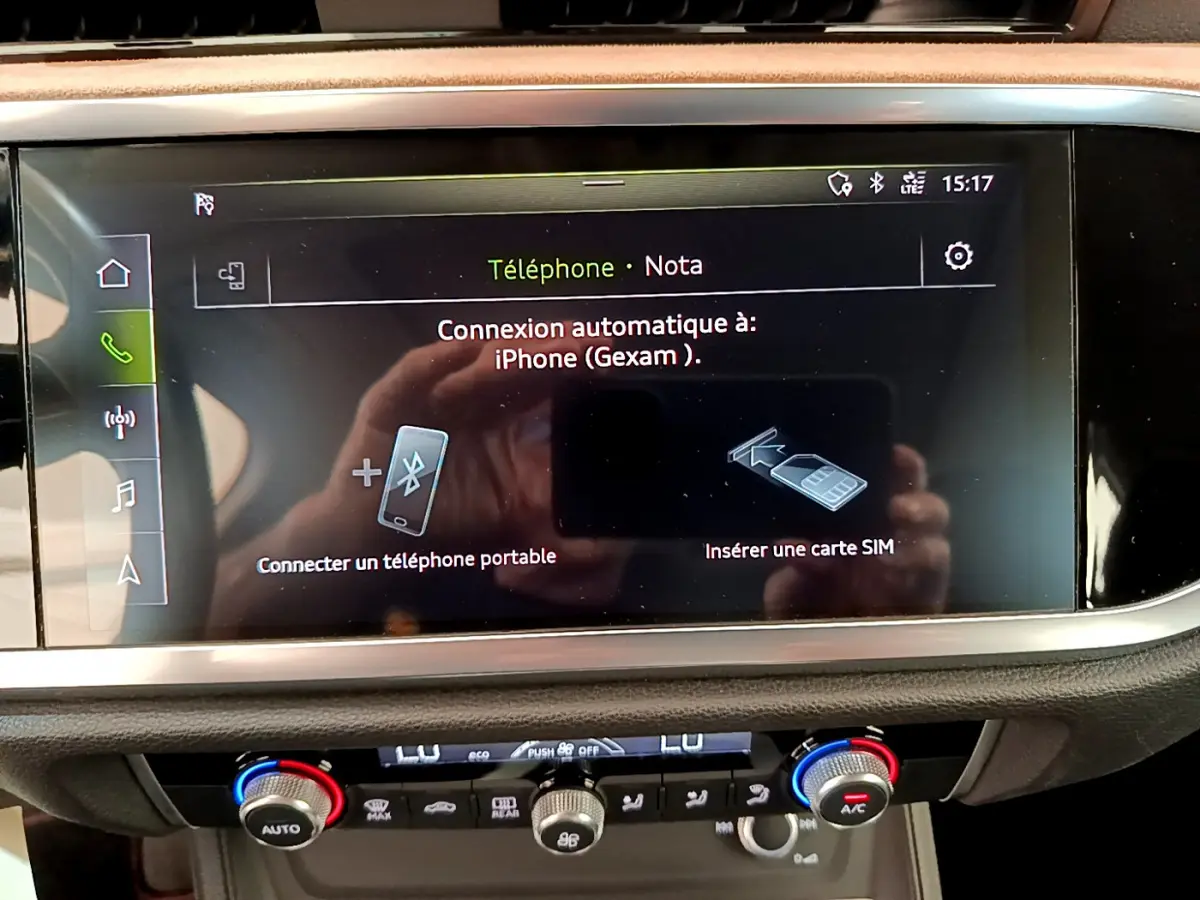 Écran tactile central affichant la connexion Bluetooth dans l'habitacle d'un Audi Q3 bleu, vue intérieure rapprochée.