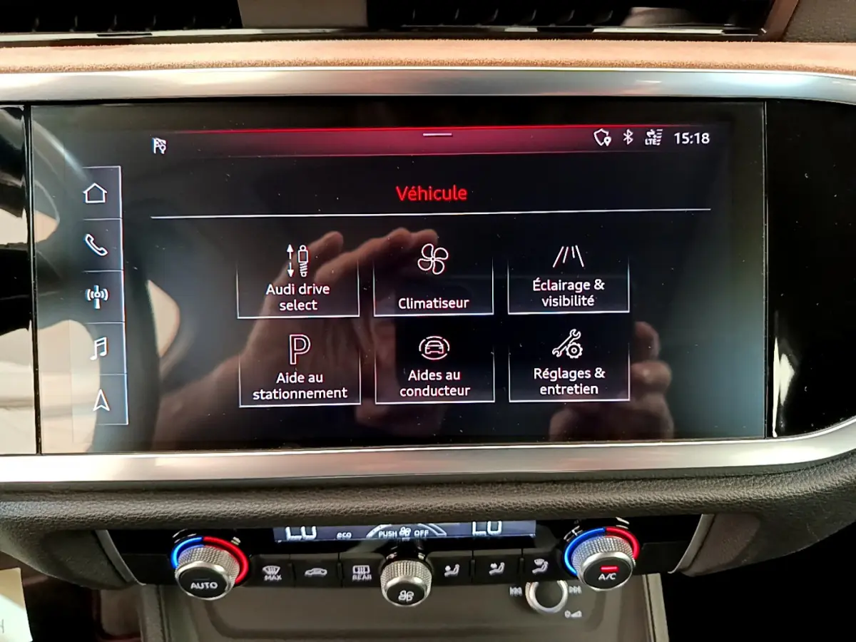 Écran tactile central de l'Audi Q3 bleu 2020 affichant les options de conduite et d'aide au stationnement.