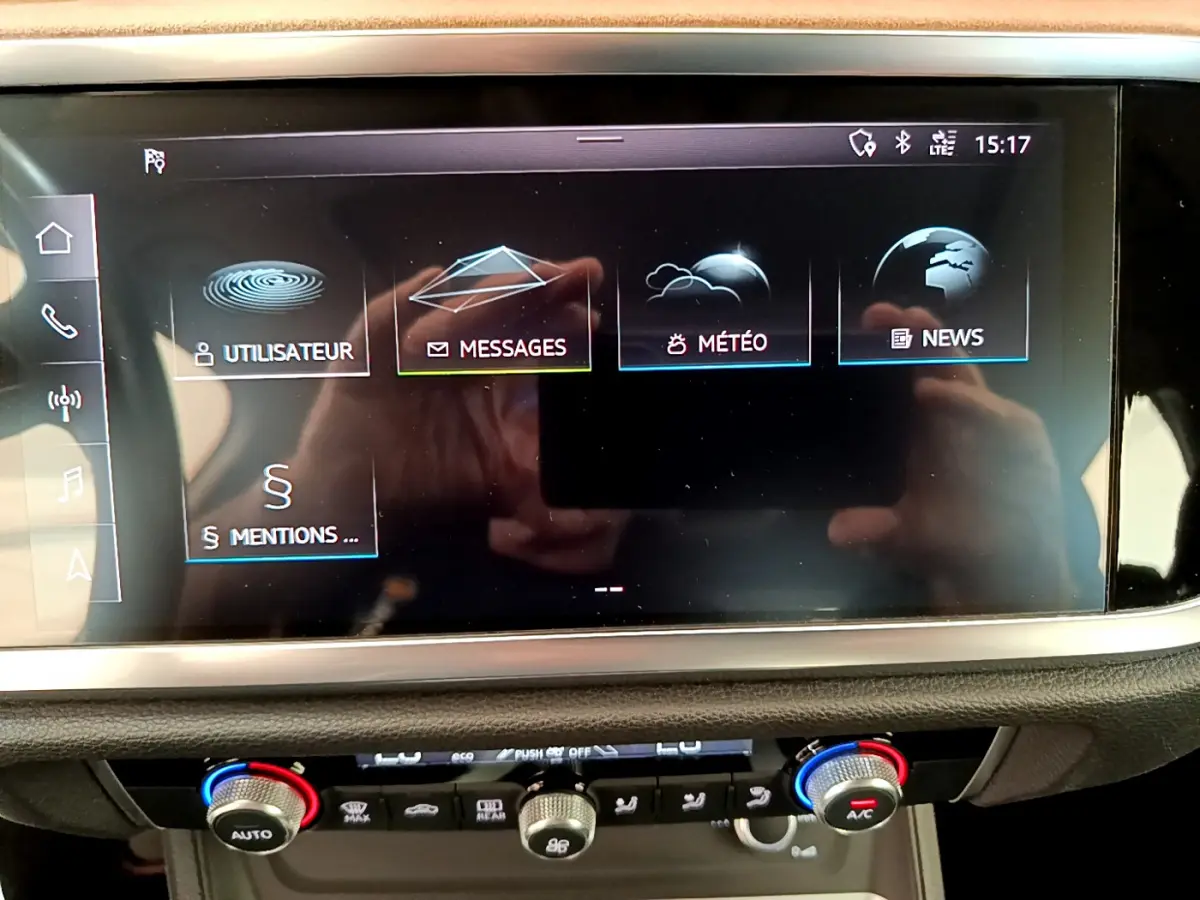 Écran tactile central affichant menu multimédia dans l’Audi Q3 bleu, vue rapprochée du tableau de bord intérieur.