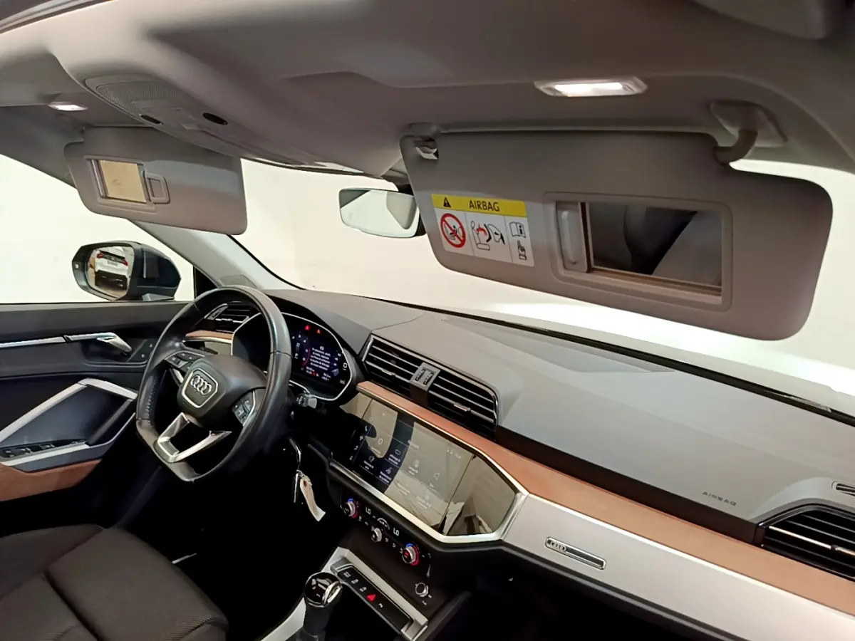 Intérieur de l'Audi Q3 35 TDI 2020 vu côté conducteur, tableau de bord moderne avec écran tactile et volant cuir noir.