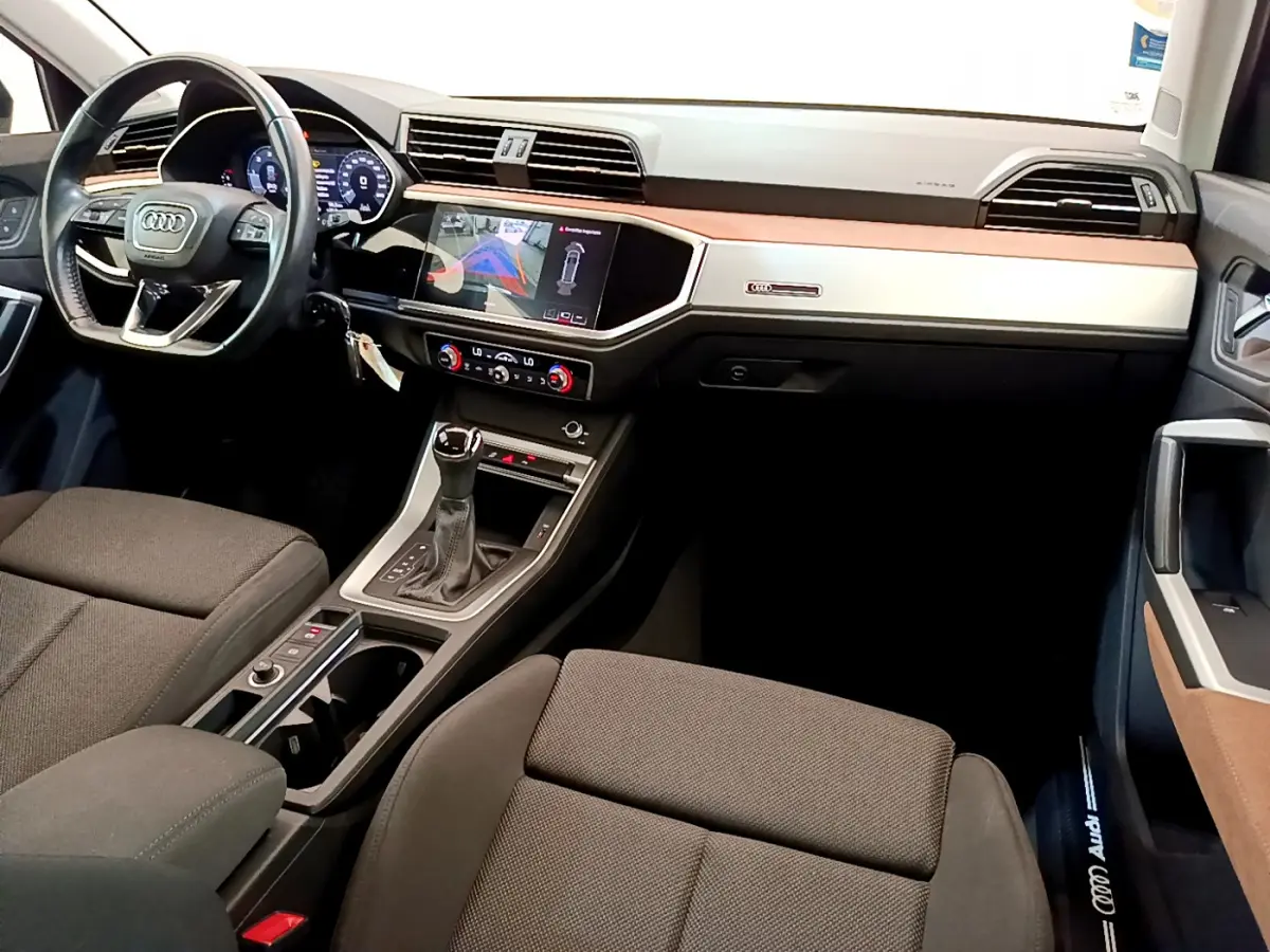 Intérieur Audi Q3 35 TDI 2020 vu de l'avant droit, tableau de bord noir et beige avec écran tactile et volant cuir noir.