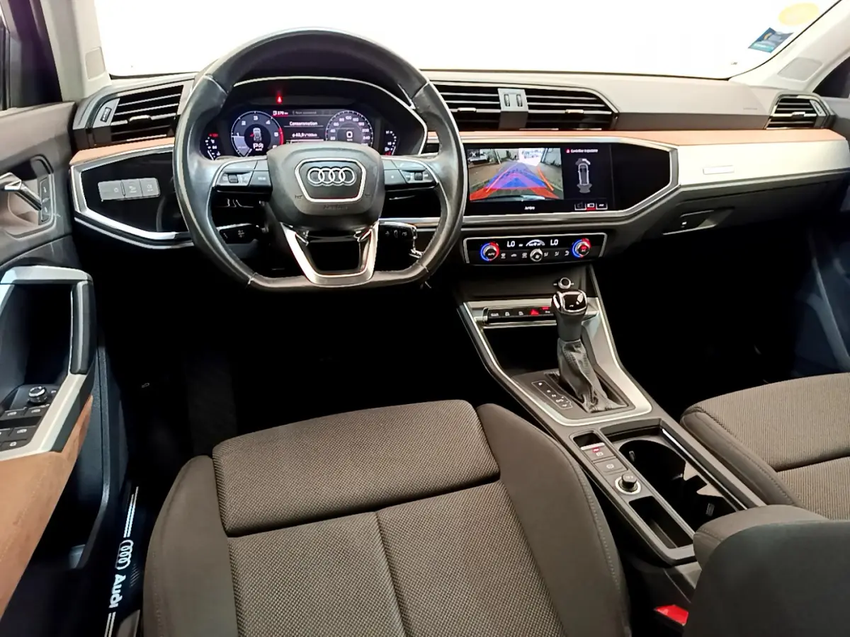 Vue intérieure avant de l'Audi Q3 35 TDI 2020, tableau de bord avec écran multimédia et volant cuir noir.
