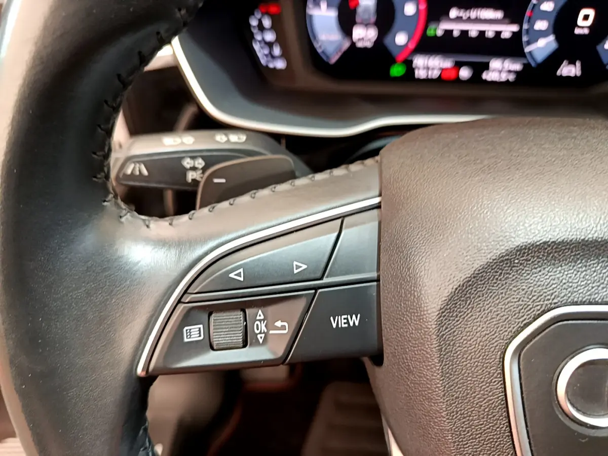 Gros plan sur les commandes gauche du volant cuir d’un Audi Q3 bleu 2020 avec tableau de bord numérique visible.