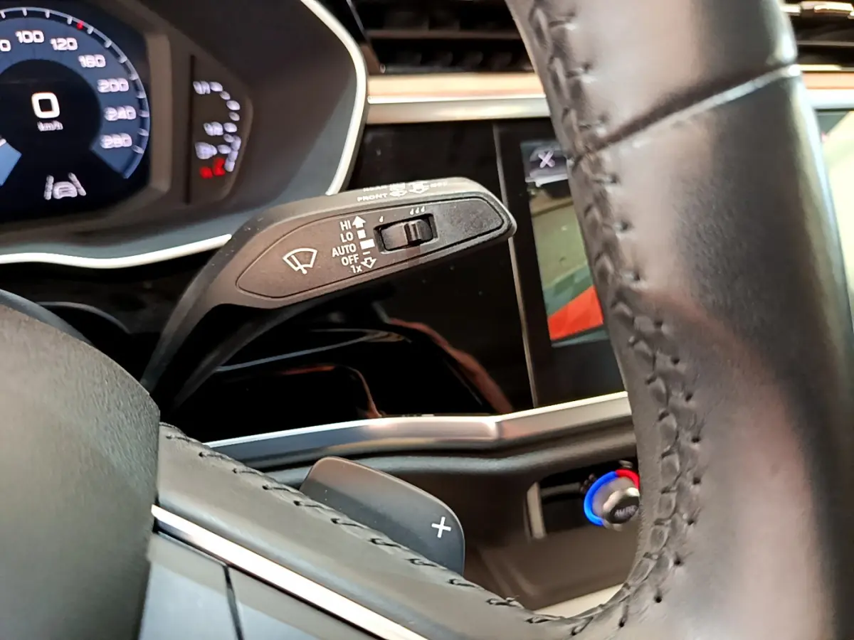 Gros plan sur le volant cuir et la manette d'essuie-glace du tableau de bord numérique d'un Audi Q3 bleu 2020