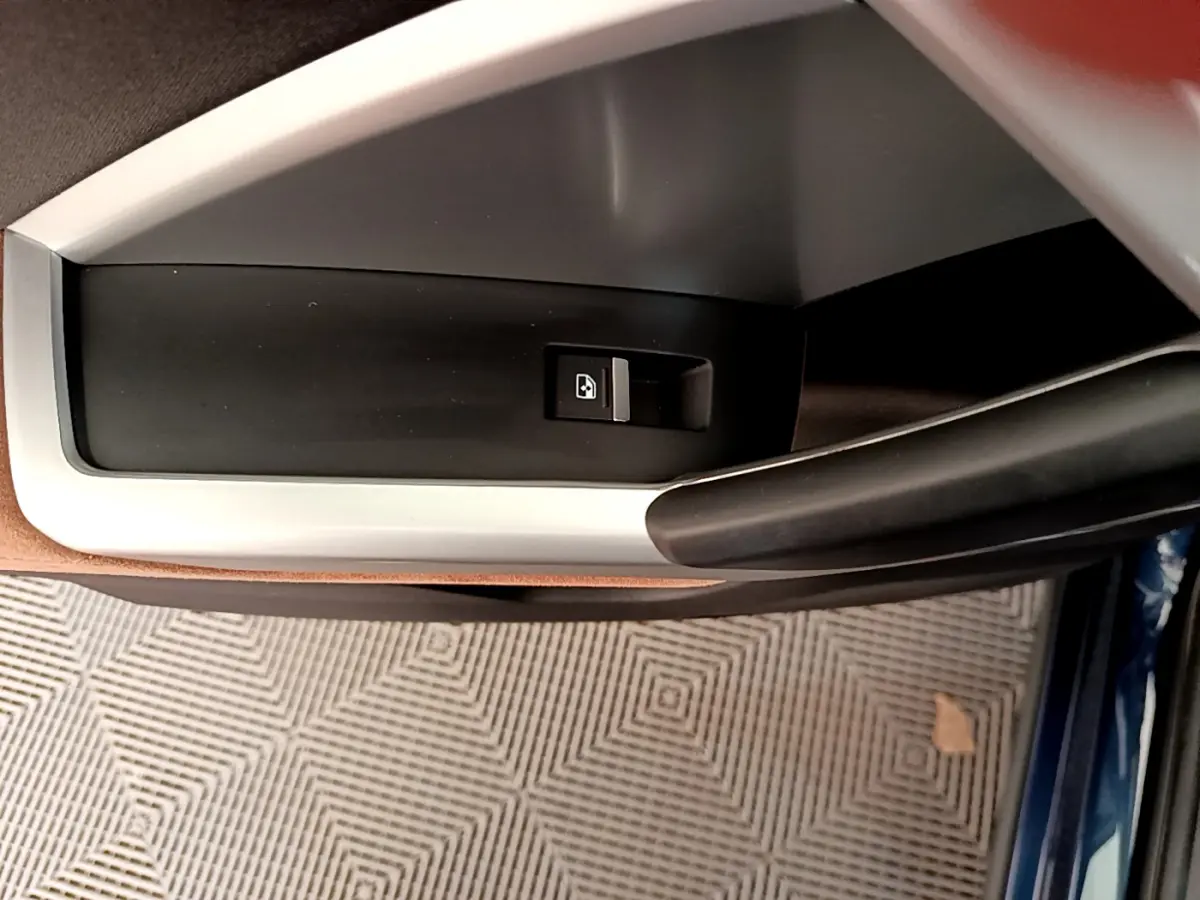 Bouton de verrouillage de porte sur la garniture intérieure côté gauche d'un Audi Q3 bleu, vue rapprochée.