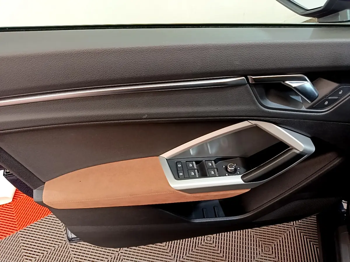 Détail de la porte côté conducteur de l'Audi Q3 35 TDI 150 S tronic Business Line 2020 avec garniture marron et commandes électriques.