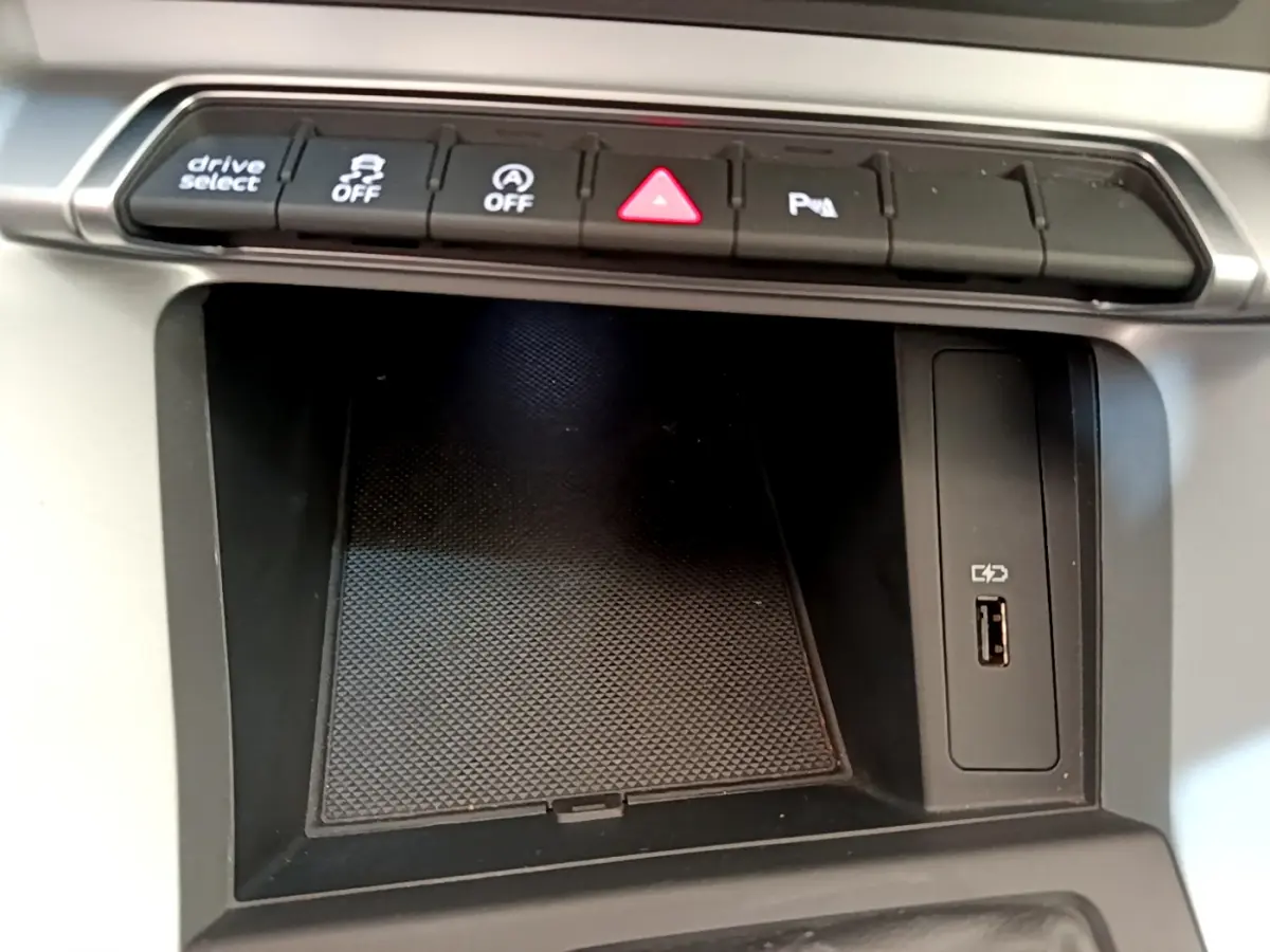Gros plan sur la console centrale noire de l'Audi Q3 35 TDI 2020 avec boutons de contrôle et port USB visible.