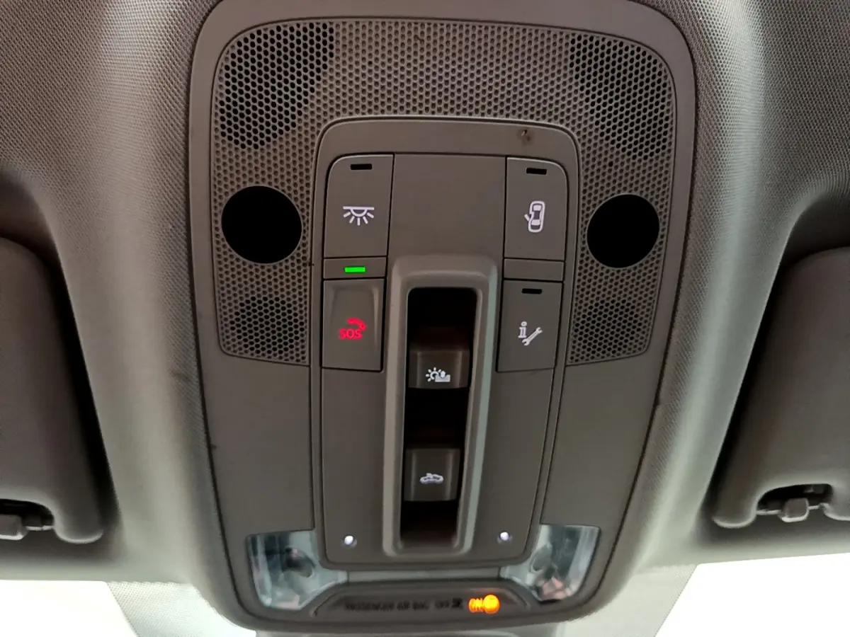 Vue en plongée sur le panneau de commandes de toit gris de l'Audi Q3 bleu, avec bouton SOS et éclairage intégré.