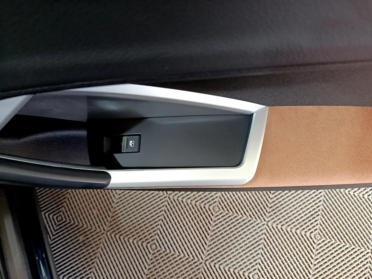 Détail de la commande de lève-vitre côté conducteur de l'Audi Q3 bleu, avec garniture beige et noire.