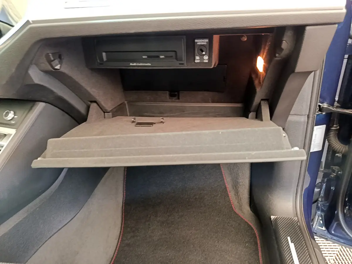 Vue intérieure côté passager de la boîte à gants ouverte d'un Audi Q3 bleu 35 TDI 2020 avec éclairage intérieur.