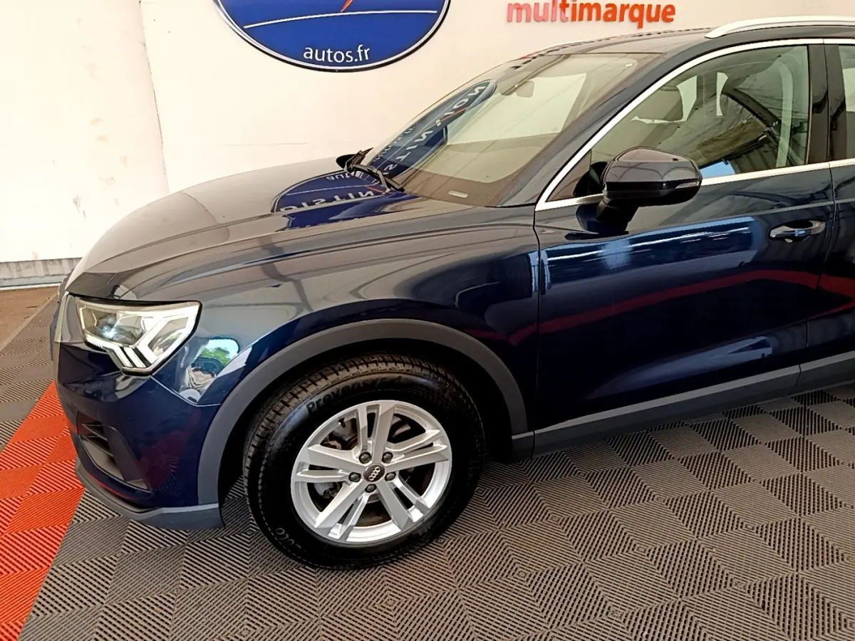 Vue de profil côté gauche d'un Audi Q3 bleu 2020 avec jante alliage et phares LED distinctifs.