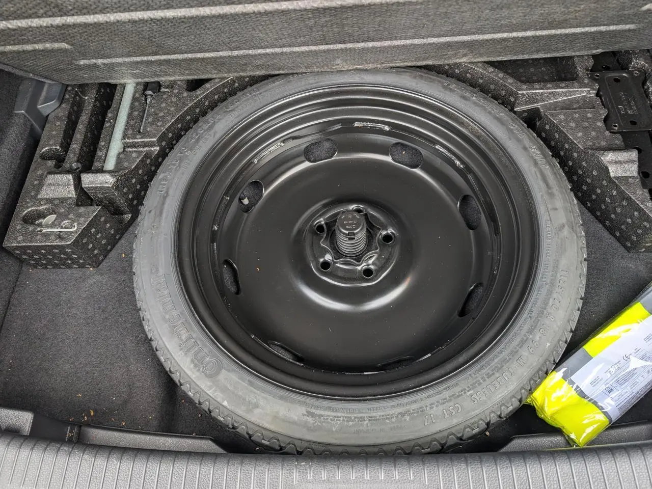 Roue de secours noire dans le coffre d'une Volkswagen Golf 2.0 TSI R 4Motion 2017, entourée d'accessoires de rangement.