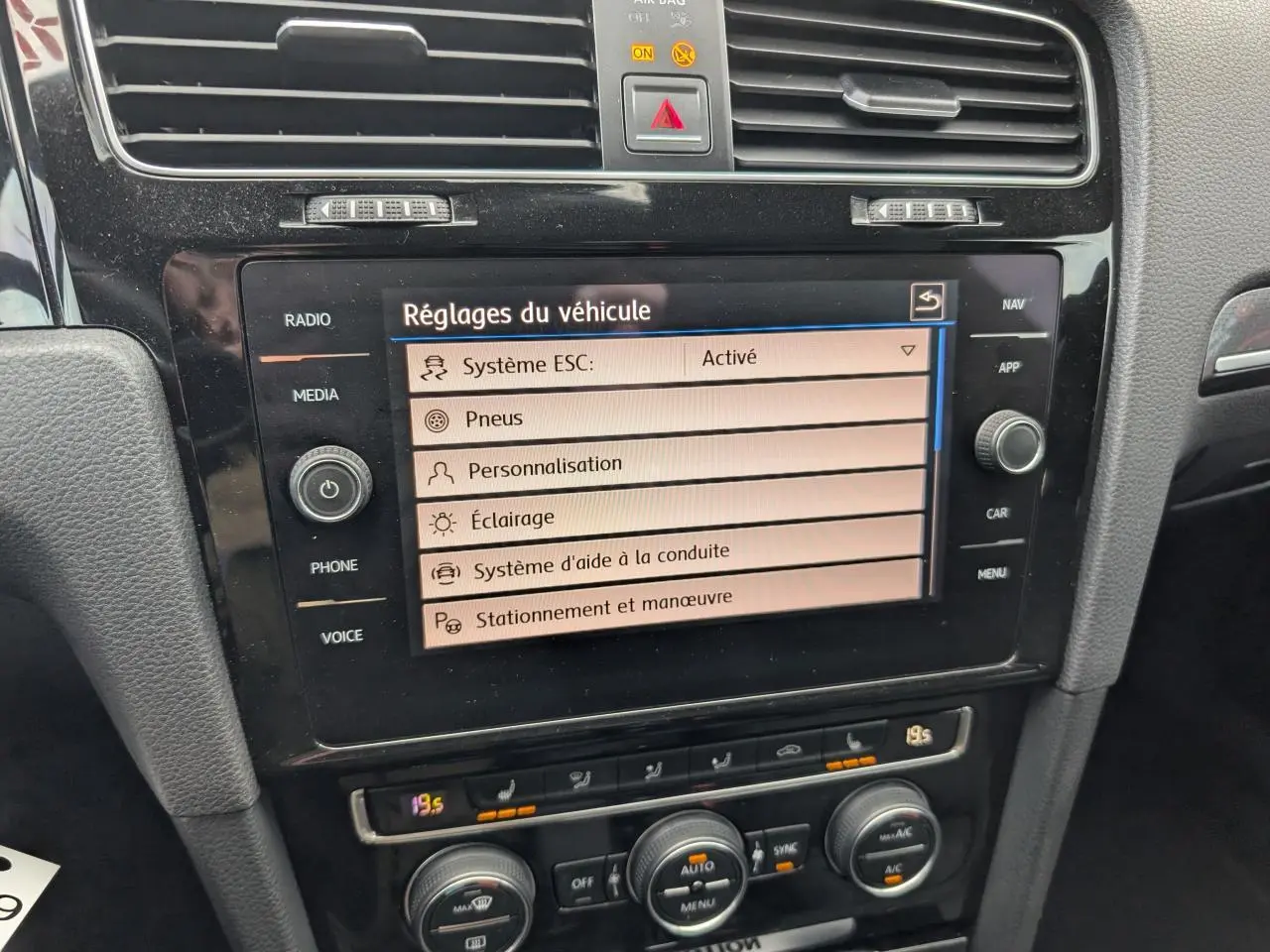 Écran central tactile affichant les réglages du véhicule dans l'habitacle noir d'une Volkswagen Golf VII R 2017.