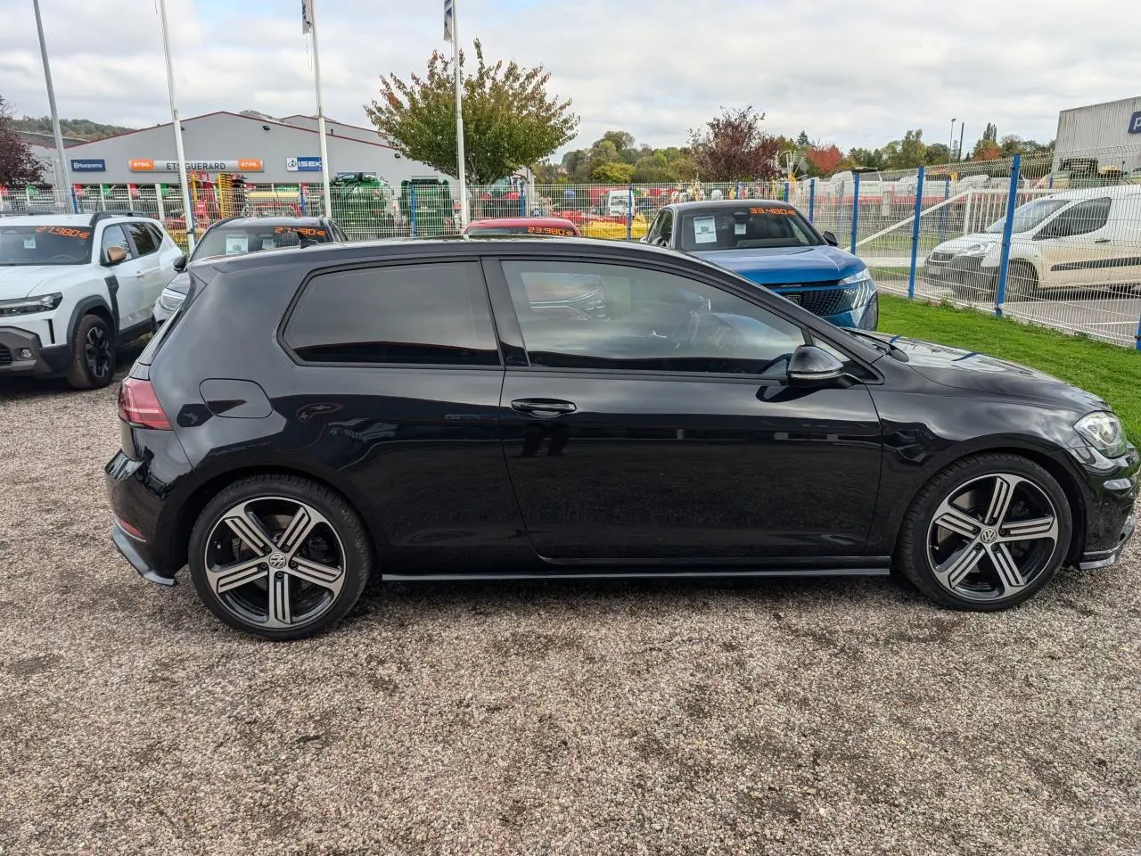 Profil droit d'une Volkswagen Golf noire 2017 avec jantes alliage 5 branches et vitres teintées.