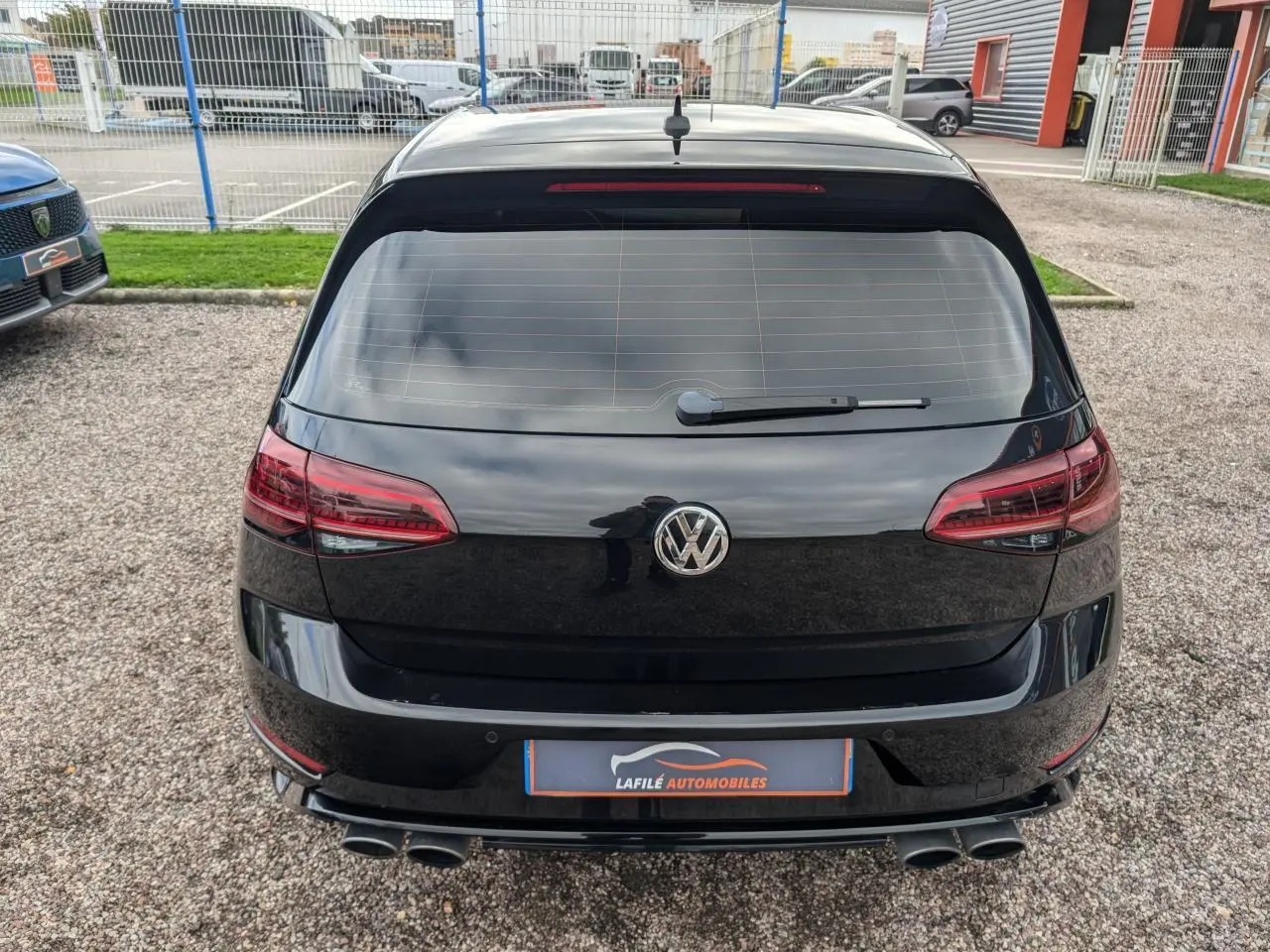 Vue arrière d'une Volkswagen Golf noire 2.0 TSI R 4Motion avec double sortie d'échappement et feux arrière LED sombres.