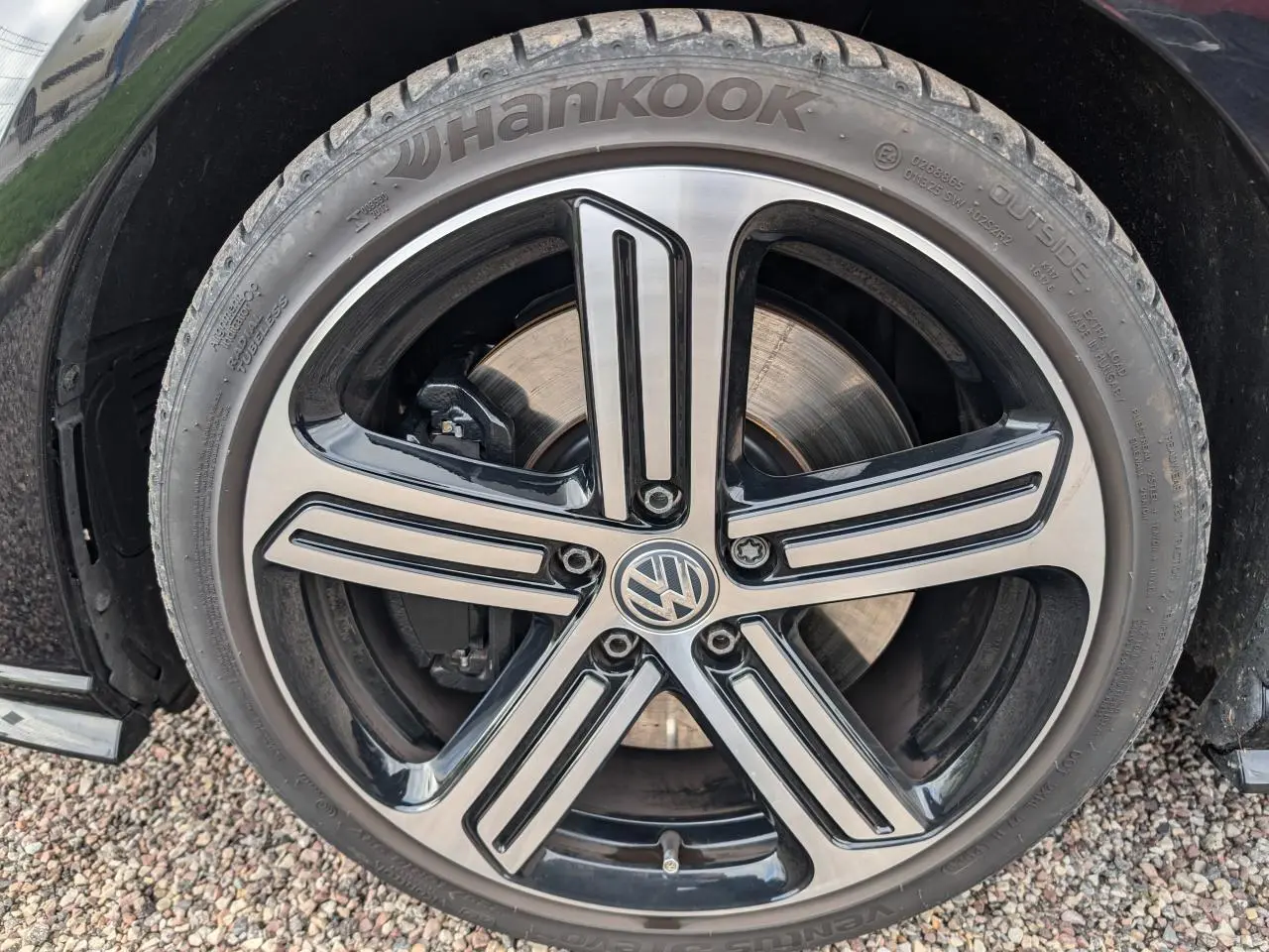 Gros plan sur la jante alliage 18'' noire et argentée avec logo Volkswagen sur une Golf noire 2017.