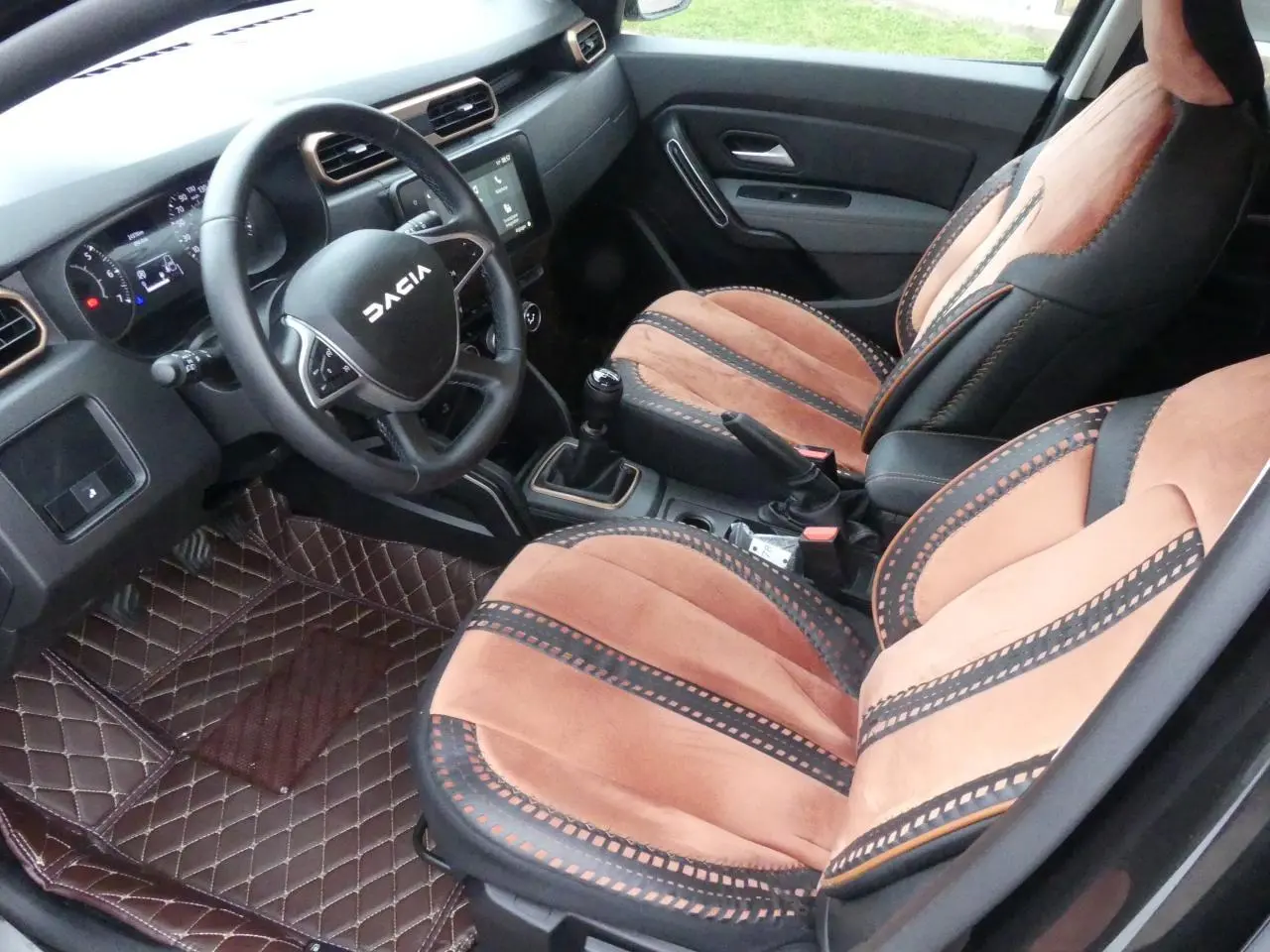 Intérieur du Dacia Duster 2023 version Extreme, vue côté conducteur, sièges marron et noir avec volant marqué DACIA.