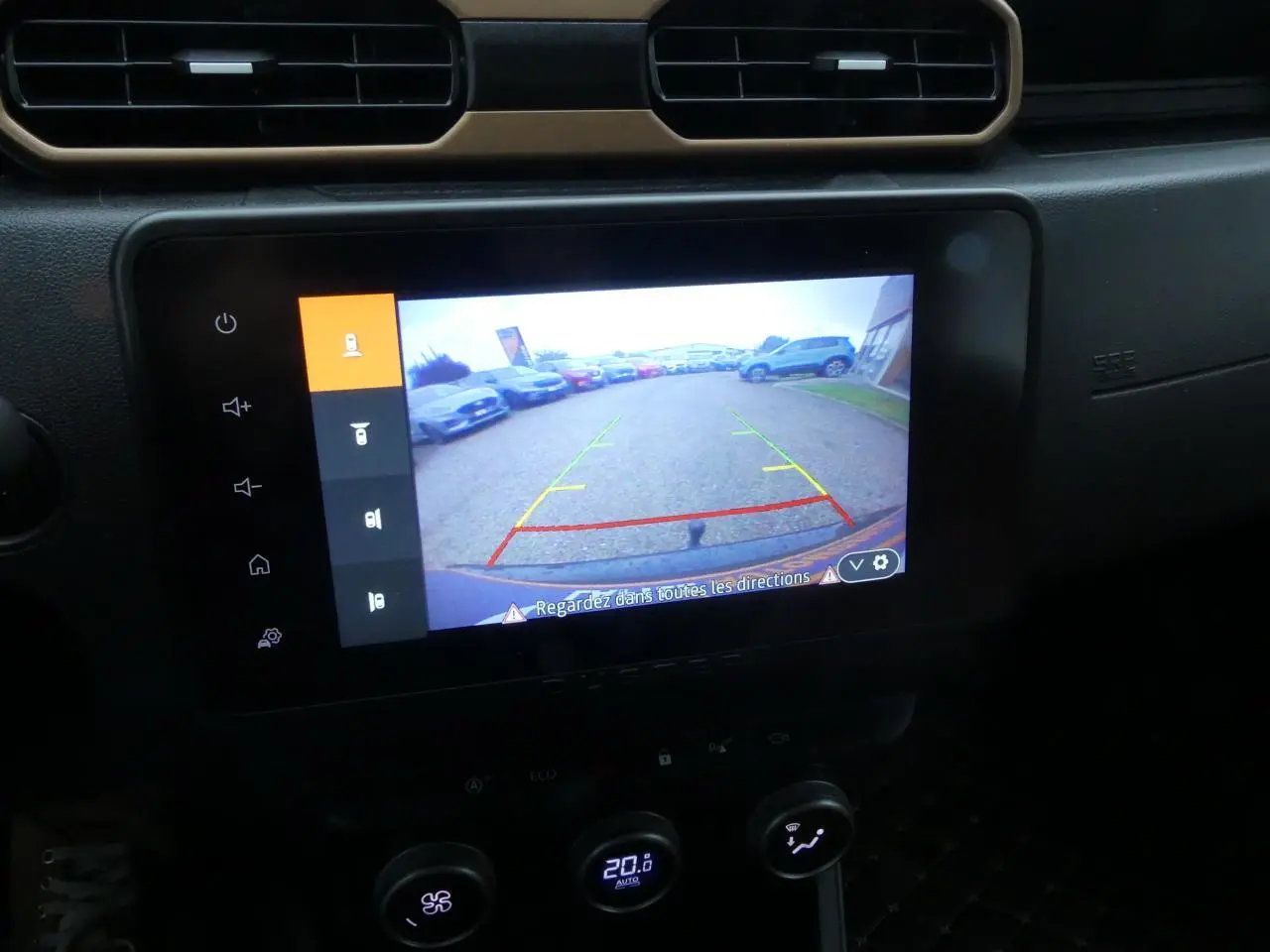 Écran central du Dacia Duster 2023 montrant la caméra de recul avec vue arrière sur un parking.