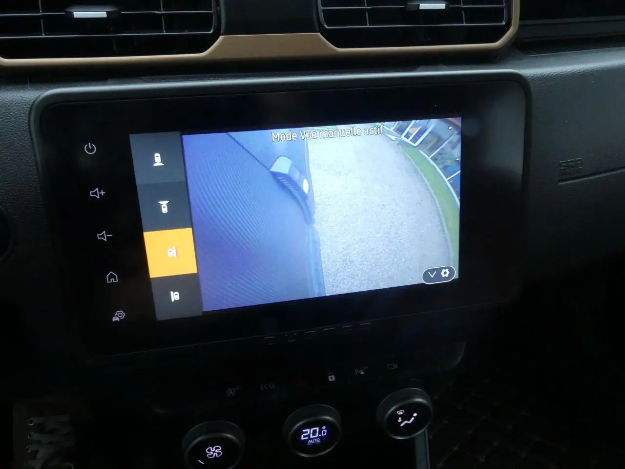 Écran central du tableau de bord du Dacia Duster noir montrant la caméra multivues côté gauche en marche.