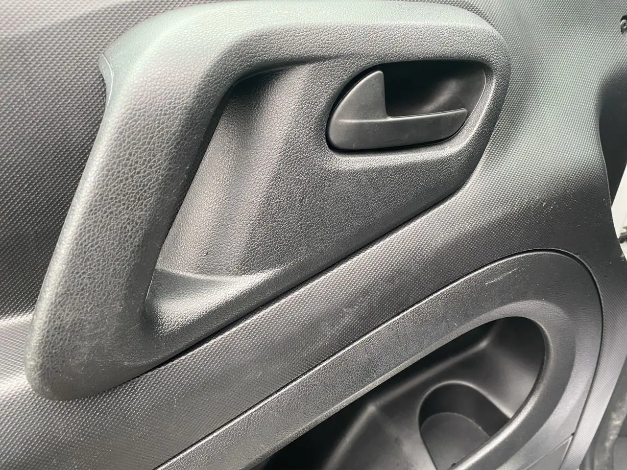 Gros plan sur la poignée intérieure de porte noire du Citroën Berlingo blanc, version Van M BlueHDi 2018.