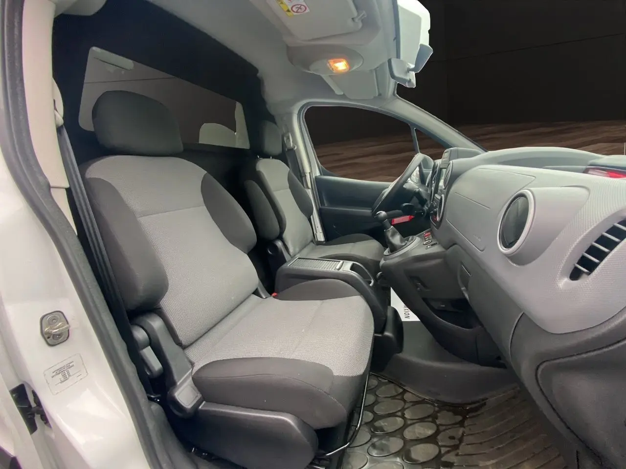 Vue intérieure côté conducteur du Citroën Berlingo blanc 2018, montrant les sièges avant et le tableau de bord simple.