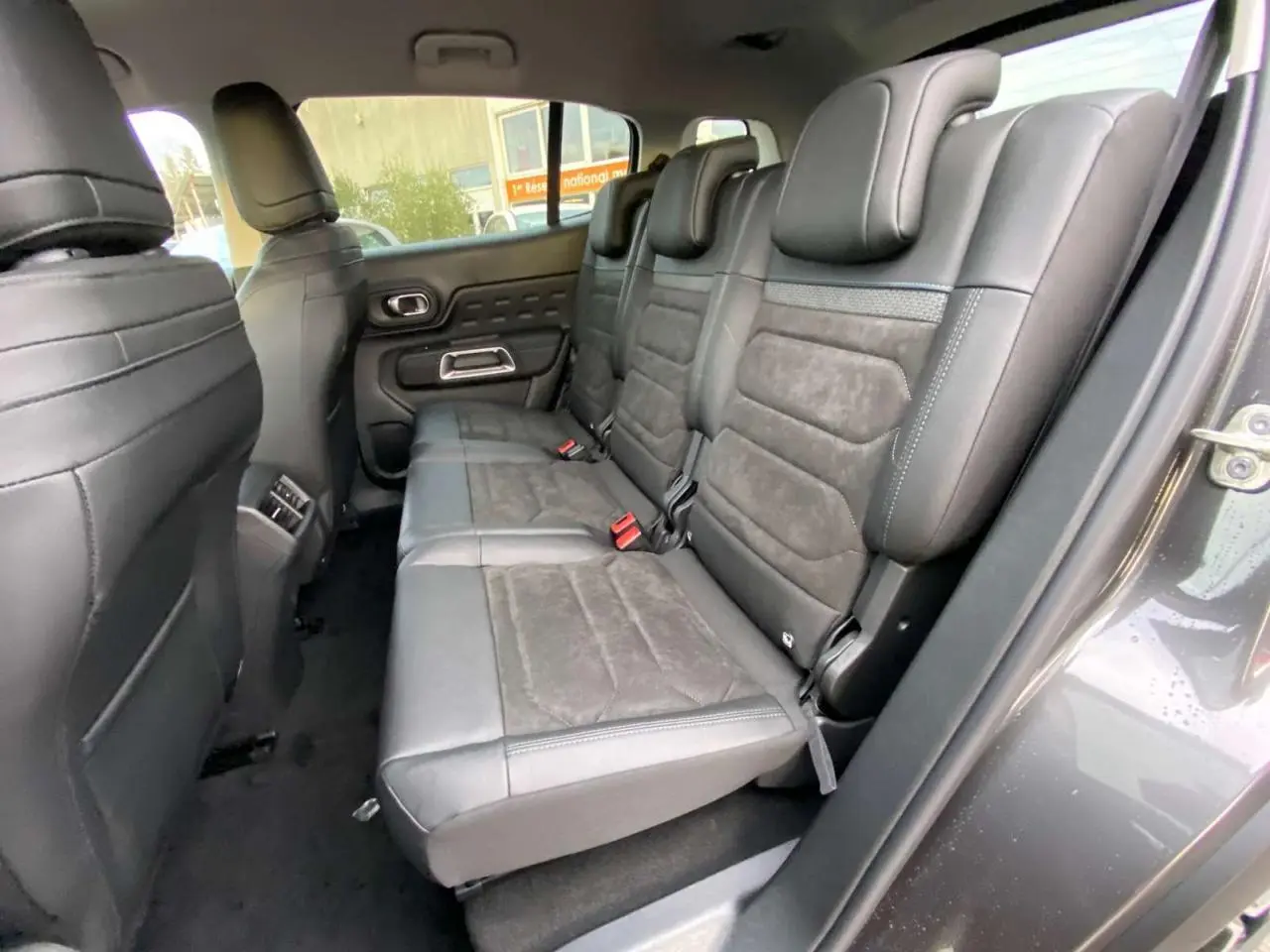 Vue intérieure côté droit sur la banquette arrière en cuir noir du Citroën C5 Aircross gris platinium, avec appuie-têtes et ceintures visibles.