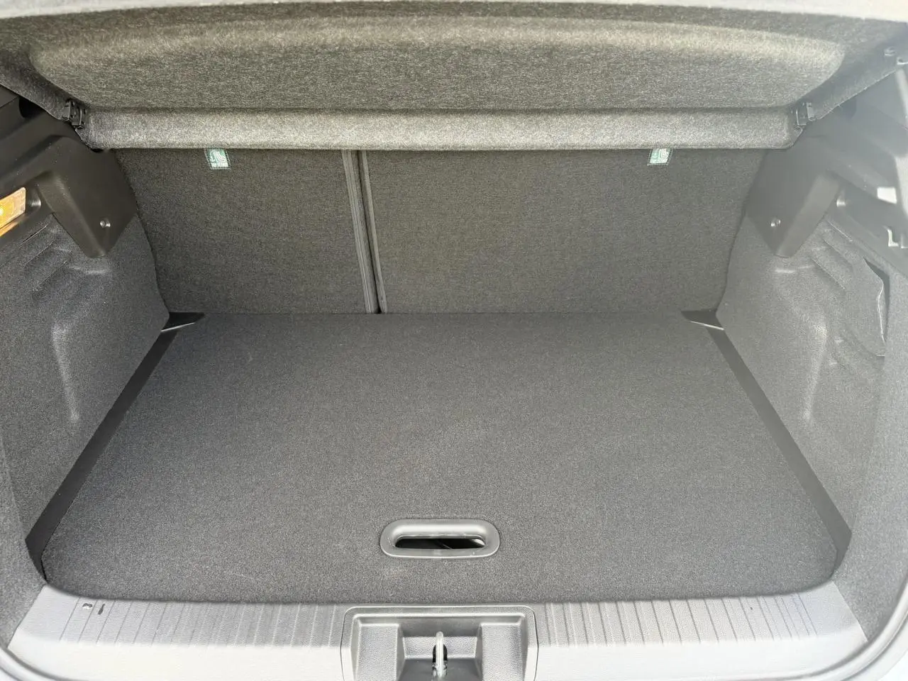 Coffre ouvert vu de face du Renault Captur gris Rafale, montrant un espace de rangement propre et vide.