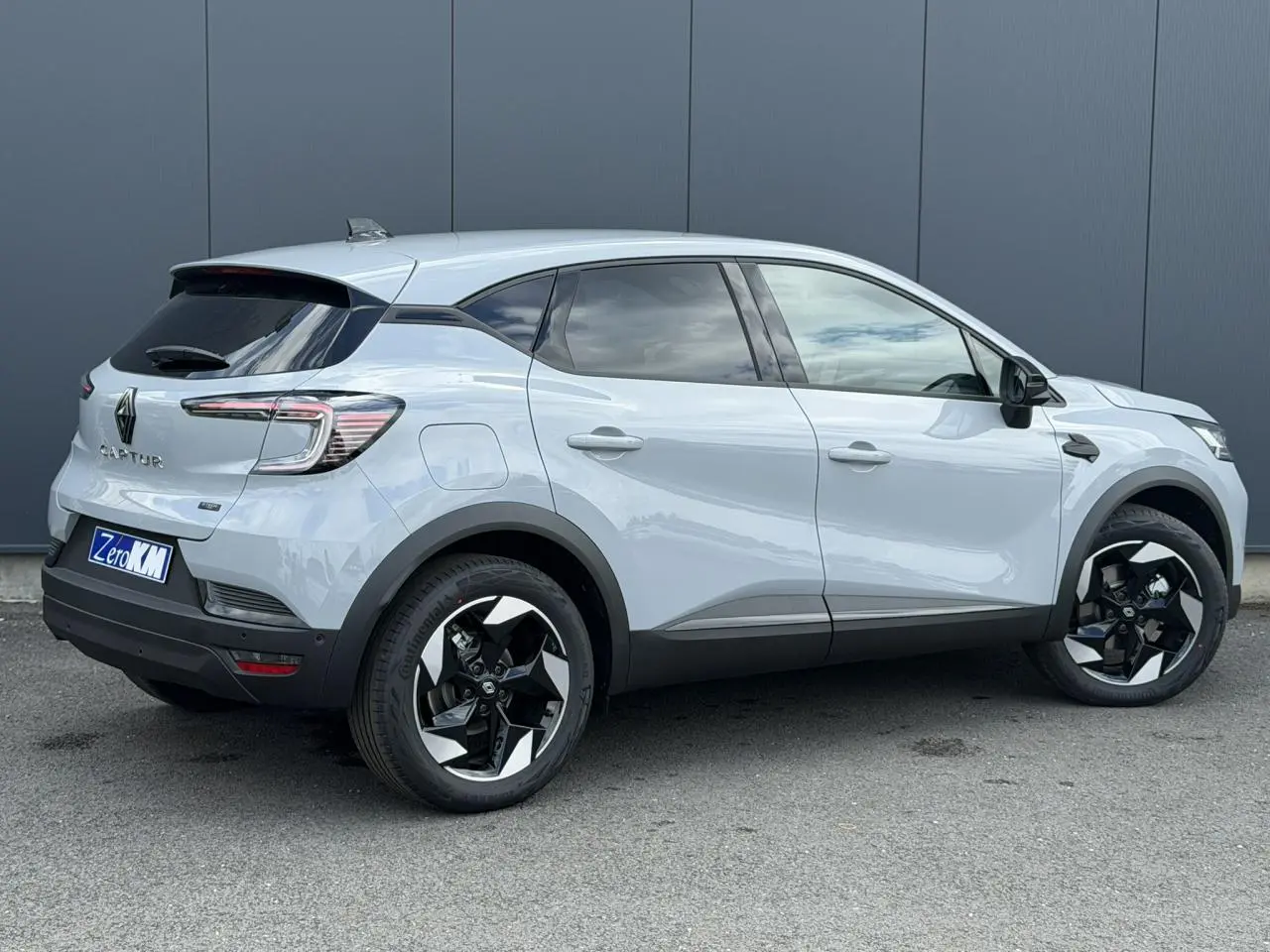 Vue 3/4 arrière droite du Renault Captur gris Rafale avec jantes noires et blanches, vitres teintées et antenne requin.