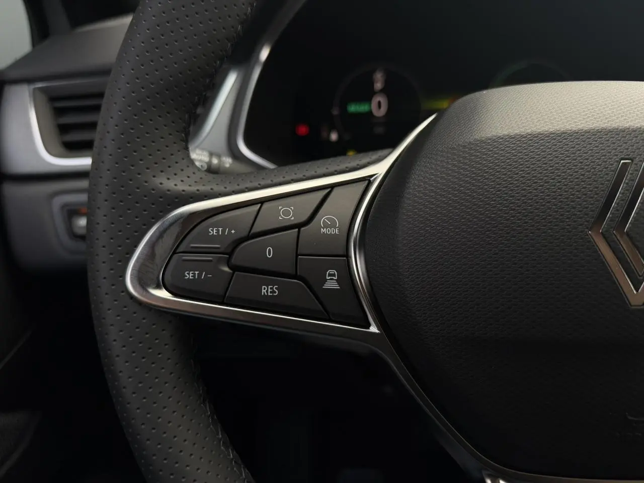 Gros plan sur le volant noir perforé du Renault Captur gris Rafale, avec commandes multifonctions à gauche visibles.