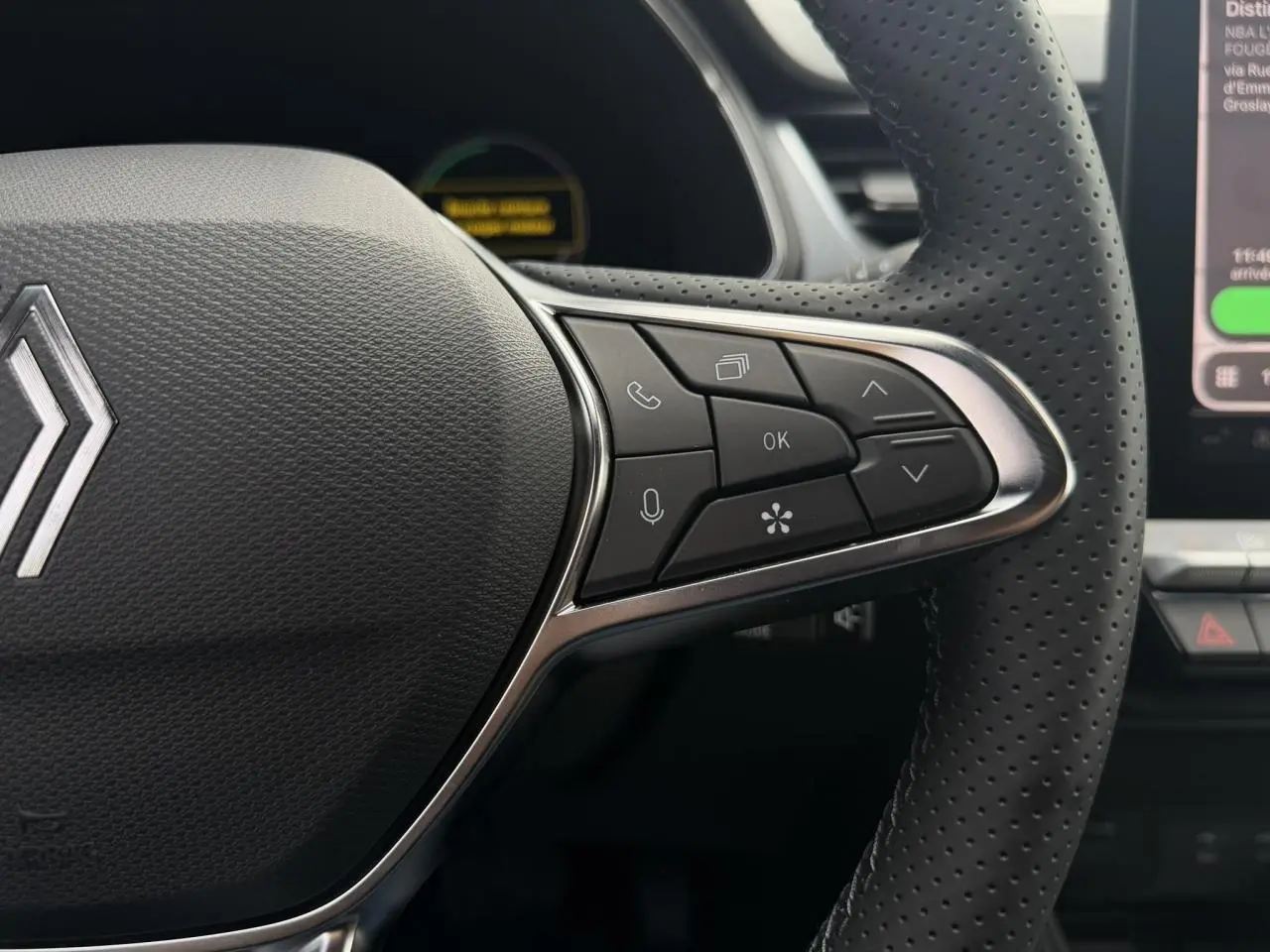 Gros plan sur le volant noir perforé du Renault Captur 2026 avec commandes multifonctions et logo central chromé.