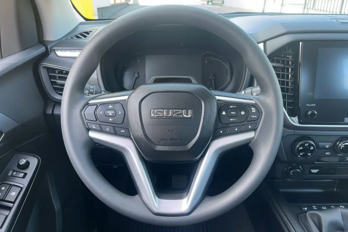 Vue intérieure centrée sur le volant multifonctions ISUZU du D-MAX 2026 avec tableau de bord et écran tactile.