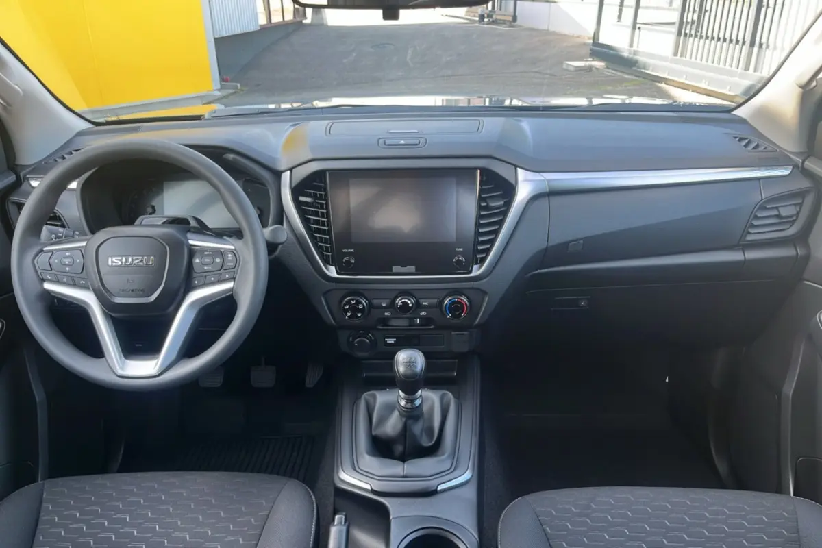 Vue intérieure avant de l'Isuzu D-MAX 2.2 TD 164 Space Evolution, tableau de bord gris avec volant multifonctions et boîte manuelle.