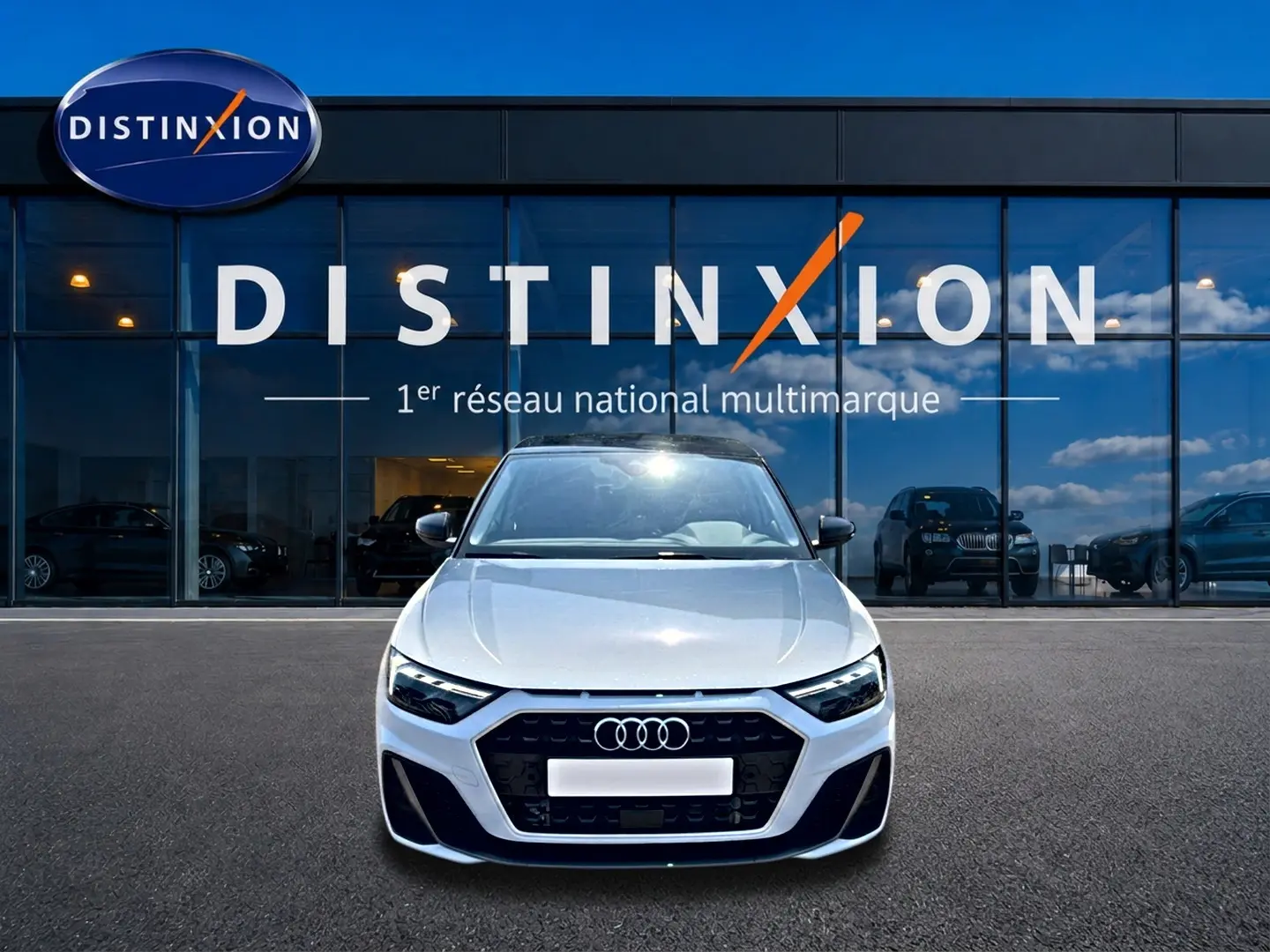 Audi A1 Sportback blanc et noir vue de face, avec calandre noire et logo Audi visible devant un showroom Distinxion.