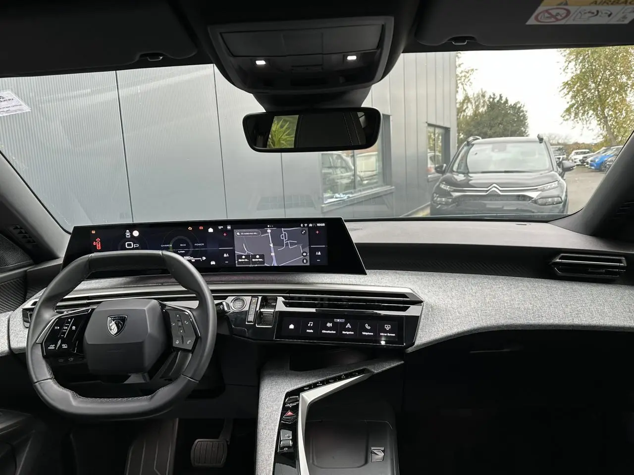 Vue intérieure avant du Peugeot 3008 Hybrid 2024 avec tableau de bord numérique panoramique et volant compact noir.