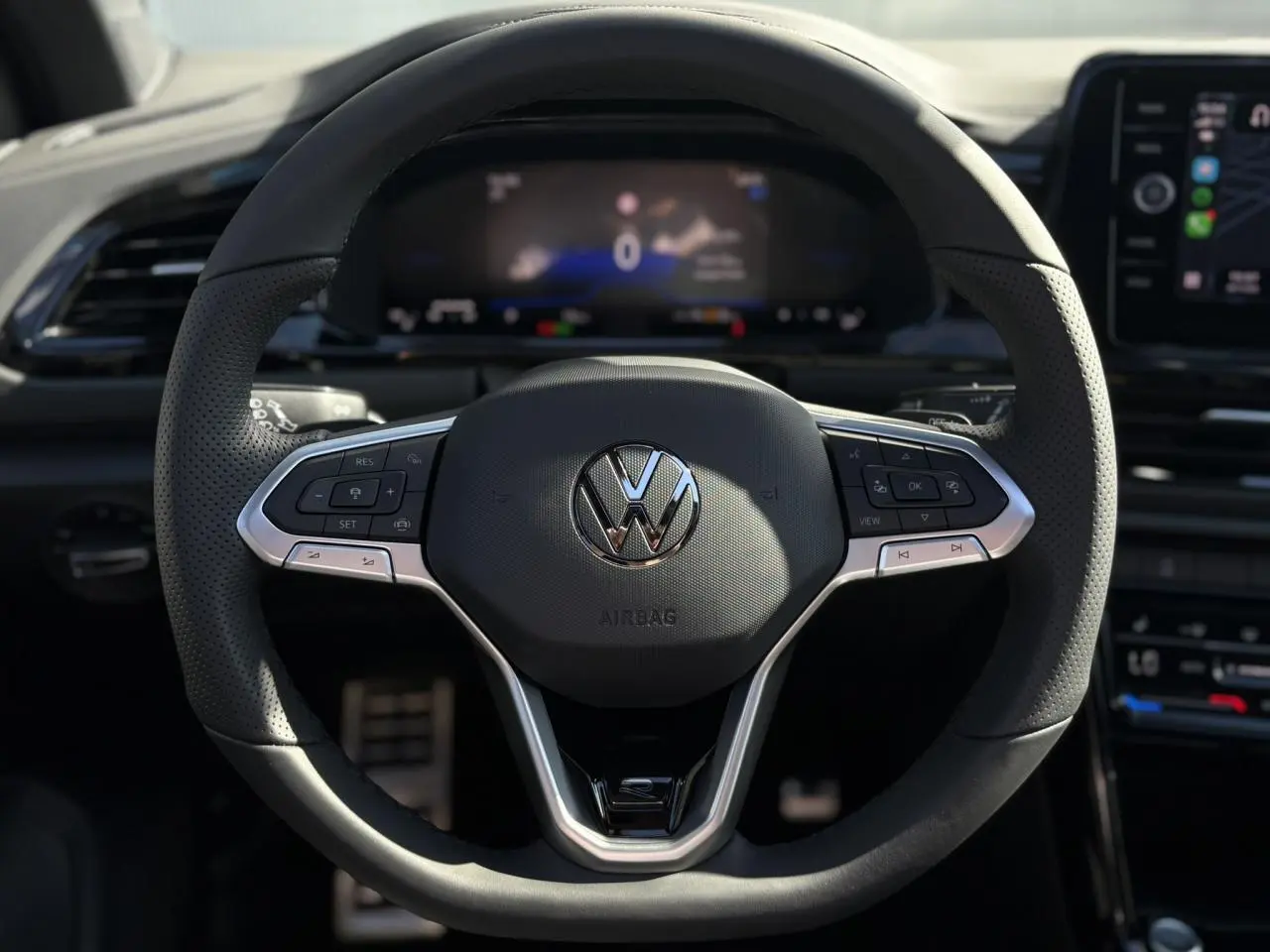 Volant sport multifonction noir avec logo VW, vue frontale centrée sur le tableau de bord numérique du Volkswagen T-Roc.