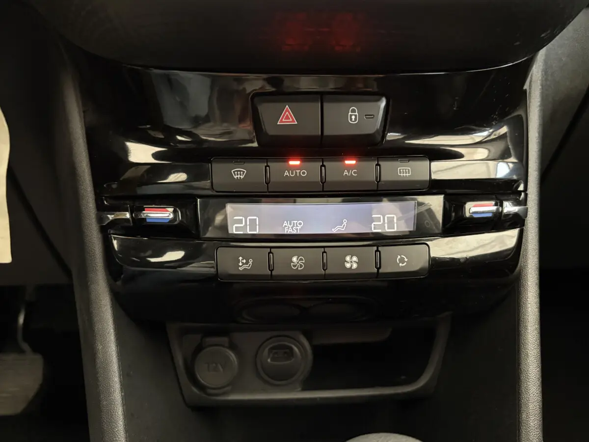 Panneau de commande de la climatisation digitale noir brillant dans l'habitacle d'une Peugeot 2008 rouge.