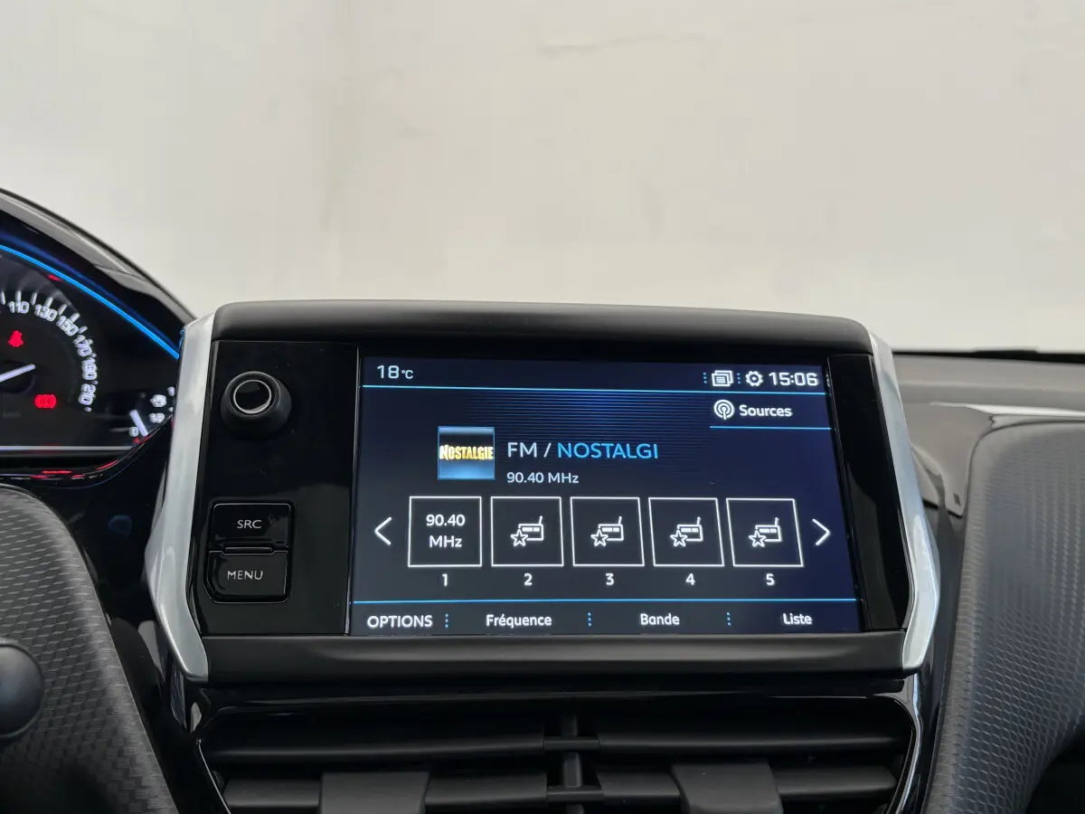 Écran tactile central affichant la radio FM dans l'habitacle du Peugeot 2008 rouge, vue de face rapprochée.