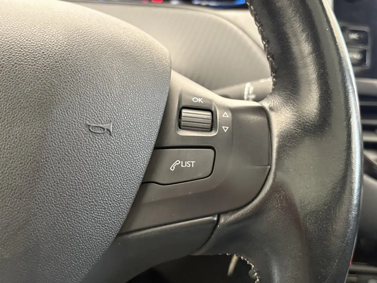 Gros plan sur le volant cuir noir du Peugeot 2008 Puretech 110 S&S EAT6 Allure de 2019, avec commandes intégrées.