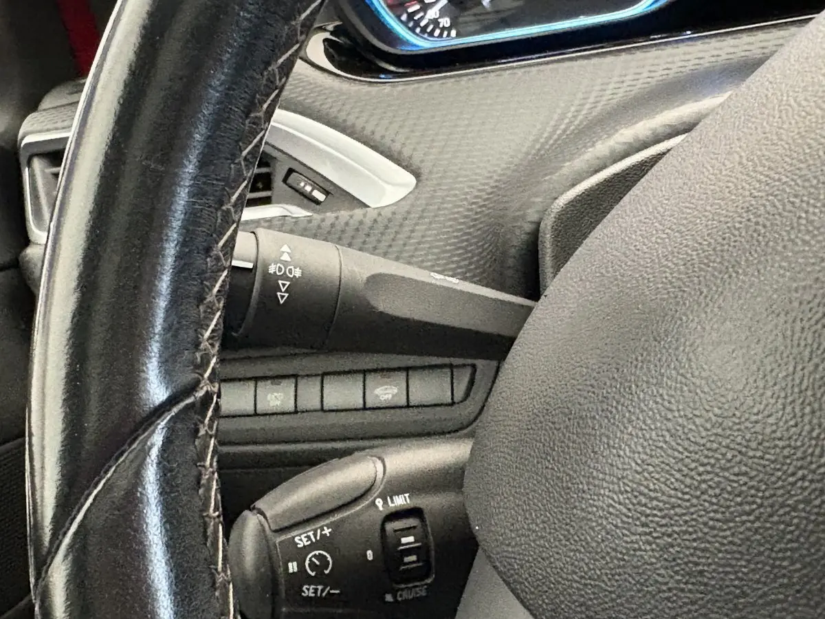Gros plan sur le volant cuir noir de la Peugeot 2008, avec commandes de régulateur de vitesse visibles.