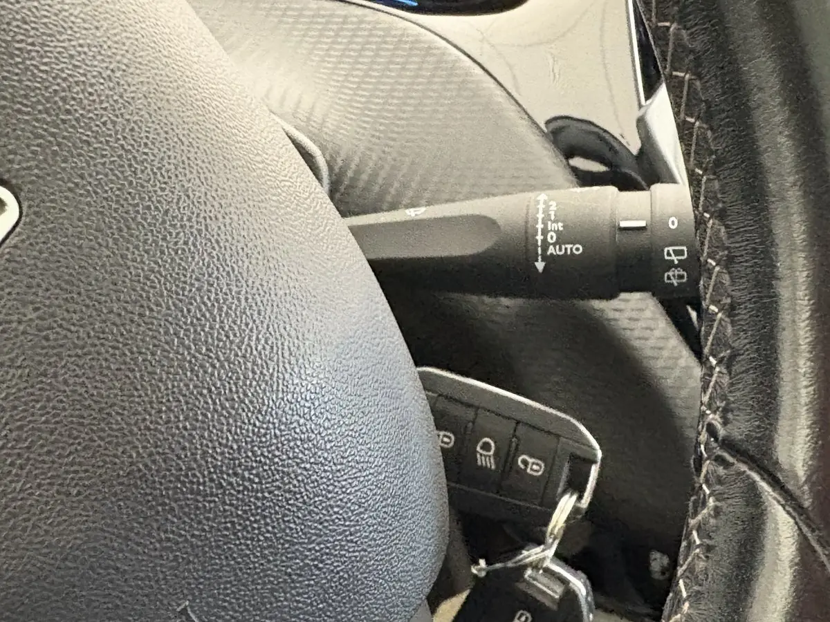 Gros plan sur le volant cuir et la commande d’essuie-glace du Peugeot 2008 rouge, version Allure 2019.